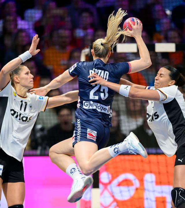 Norwegens Henny Ella Reistad setzt zum Wurf aus dem Sprung auf das deutsche Tor an, wird dabei aber von den deutschen Handballnationalspielerinnen Viola Leuchter und Aimee von Pereira behindert.