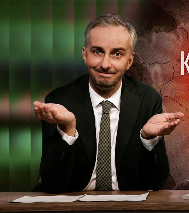 Jan Böhmermann sitzt am Schreibtisch. Rechts im Hintergrund ist eine Landkarte mit dem geografischen Umriss Irans zu sehen. Darüber steht der Text "Krieg um Iran".