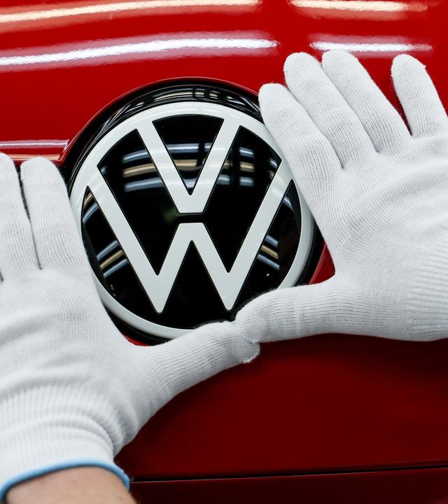 Die Hände eines Mitarbeiters berühren ein Volkswagen Logo
