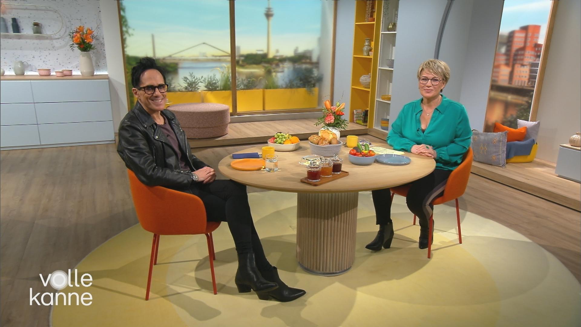 Musiker Andy Brings mit Moderatorin Andrea Ballschuh sitzen am Frühstückstisch im Volle-Kanne-Studio.