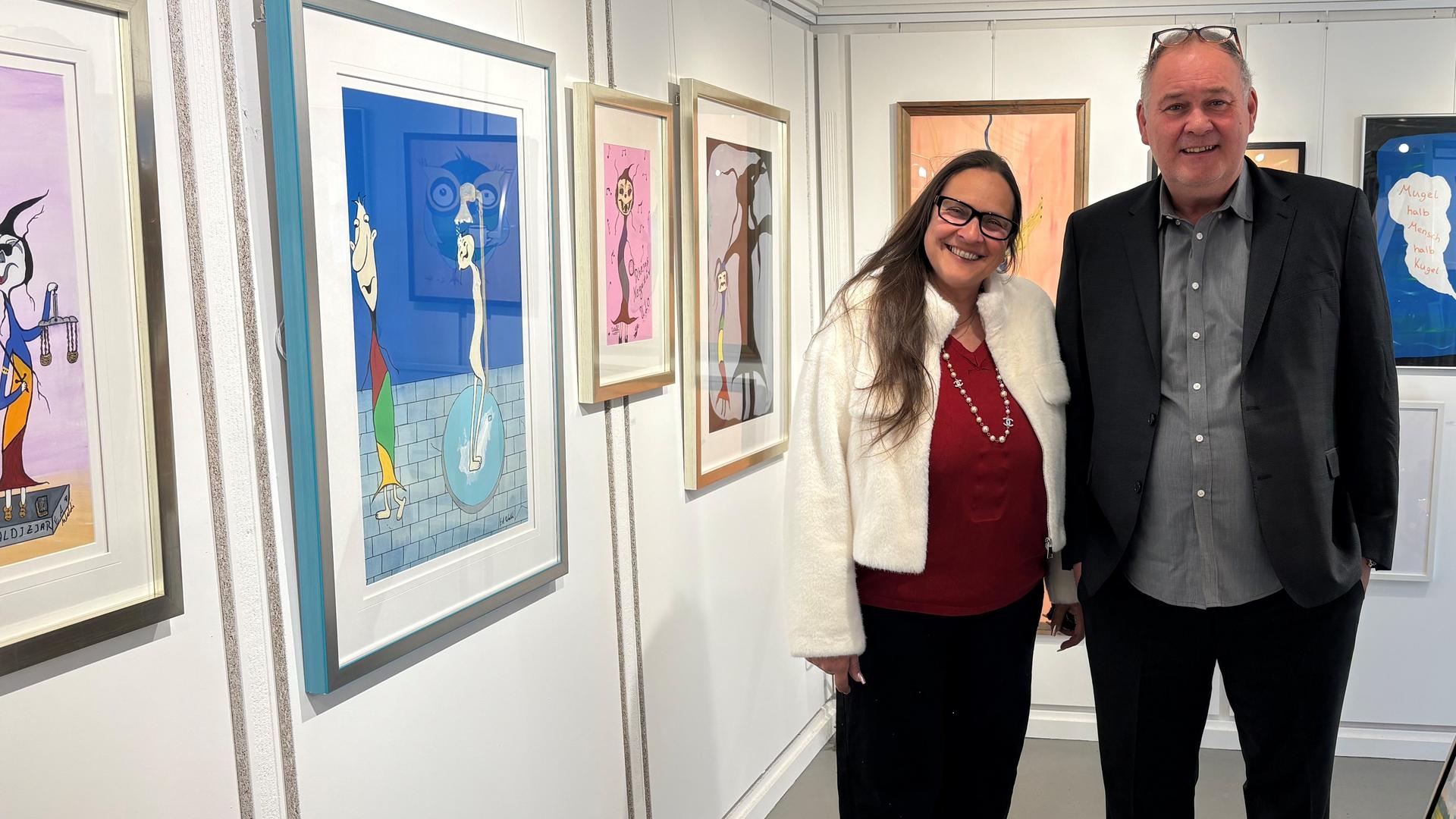 Sonja und Waldi (v. l. n. r.) stehen in einer Kunst-Galerie und lächeln in die Kamera.