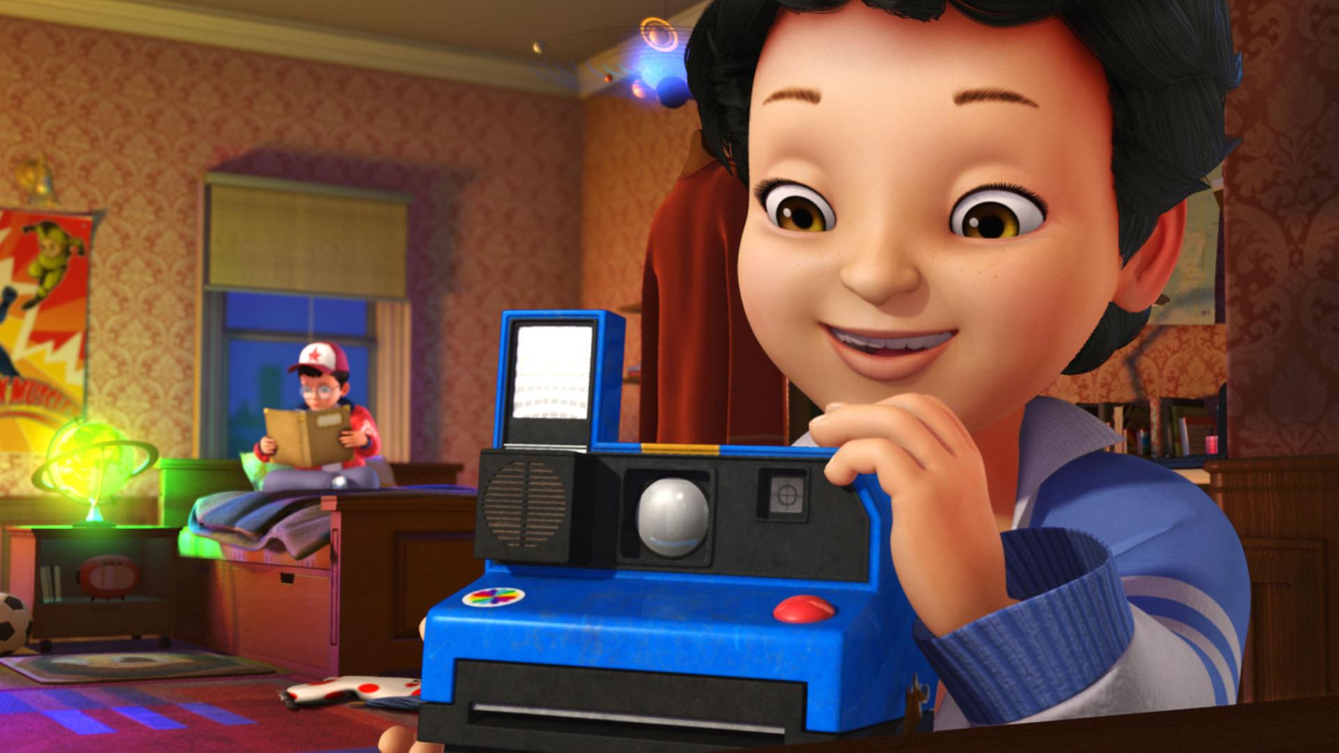 Michael mit einer blauen Sofortbild-Kamera. John sitzt im Hintergrund auf dem Bett und liest in einem Buch.