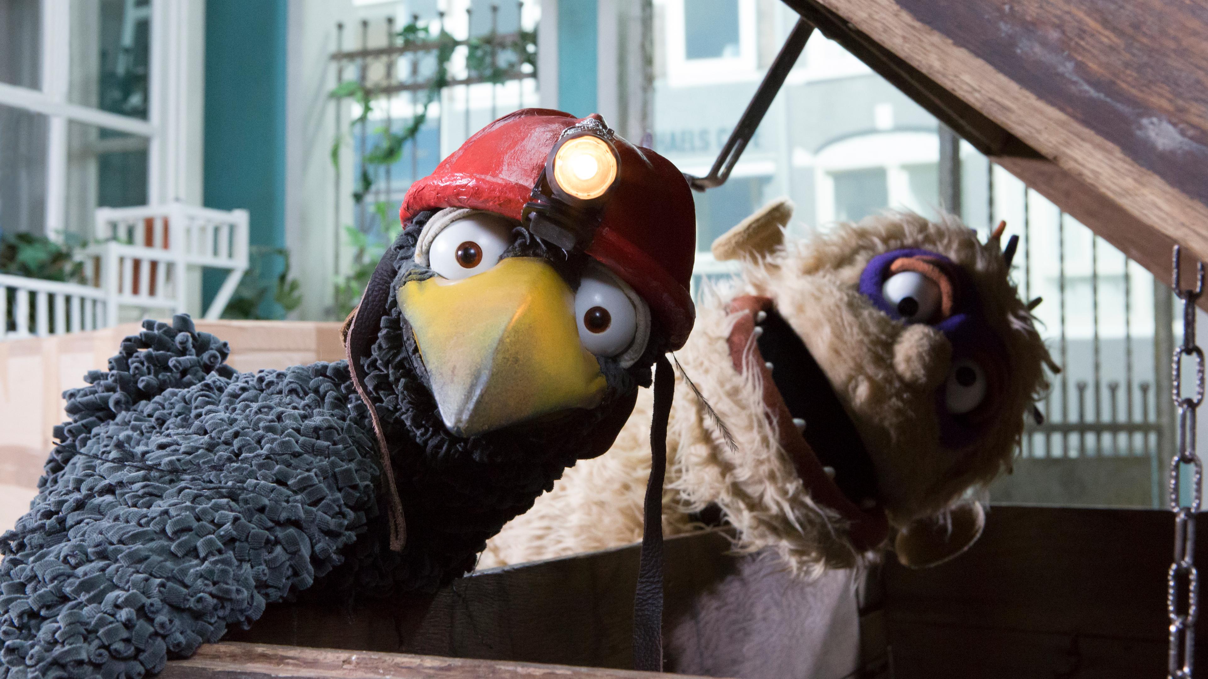 Monster und Rabe Rudi, mit Helm und Lampe auf dem Kopf, schauen erschrocken über die geöffnete Truhe hinweg.