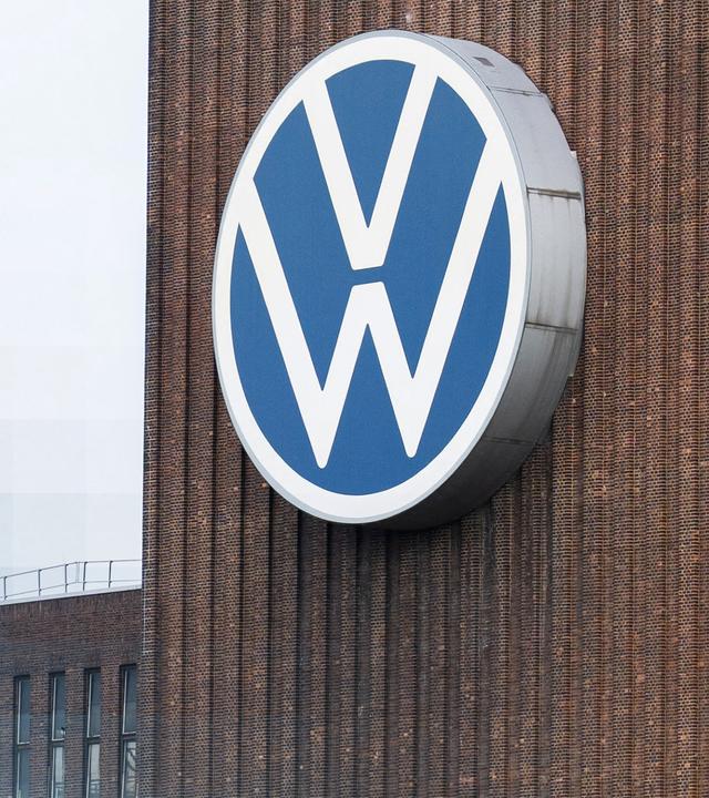 VW Zeichen an einem Gebäude. Im Hintergrund ein Baukran