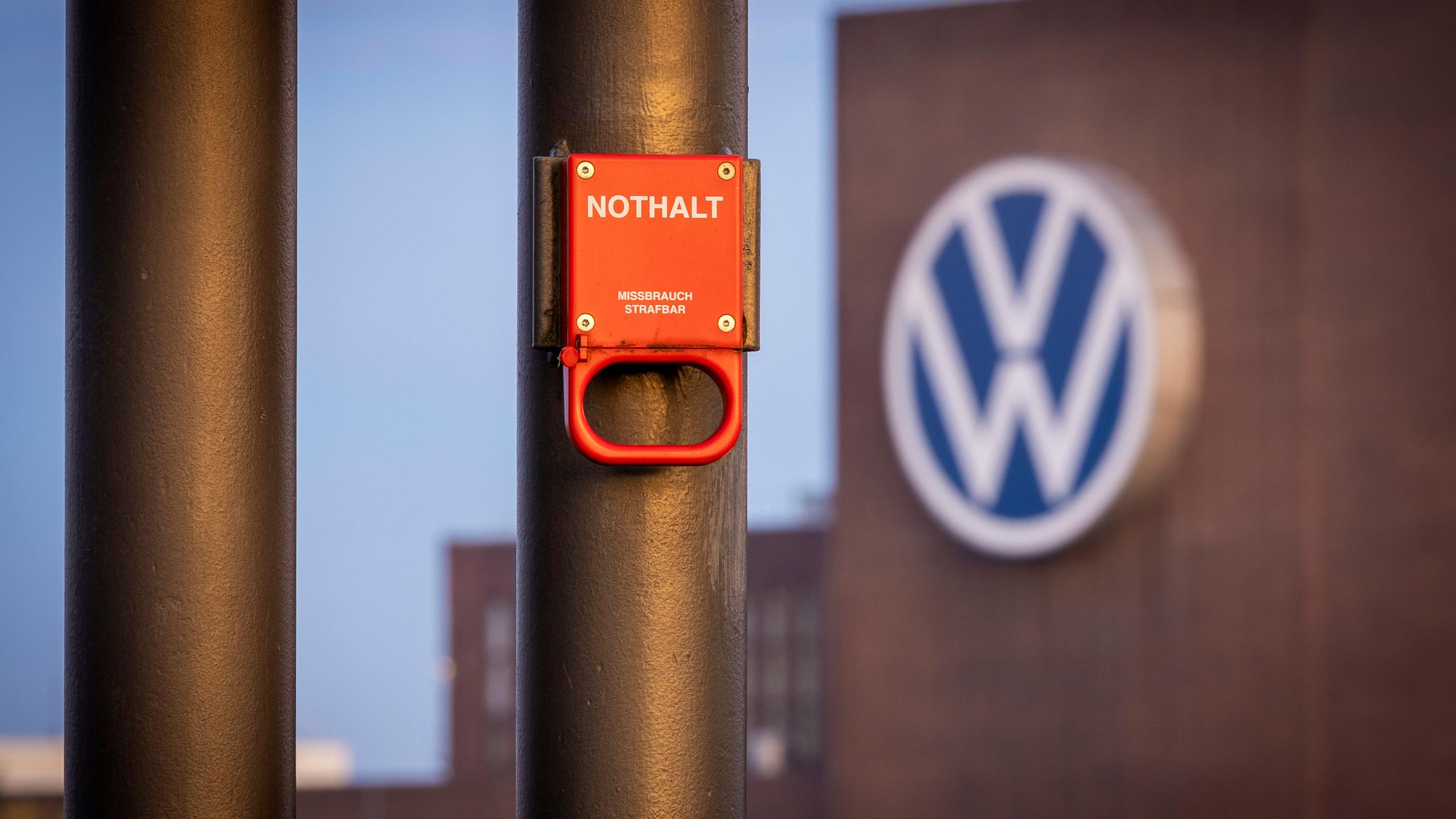 Niedersachsen, Wolfsburg: Ein Schalter mit der Aufschrift "Nothalt" ist am Morgen am Bahnhof vor einem Logo am Volkswagen-Stammwerk zu sehen.