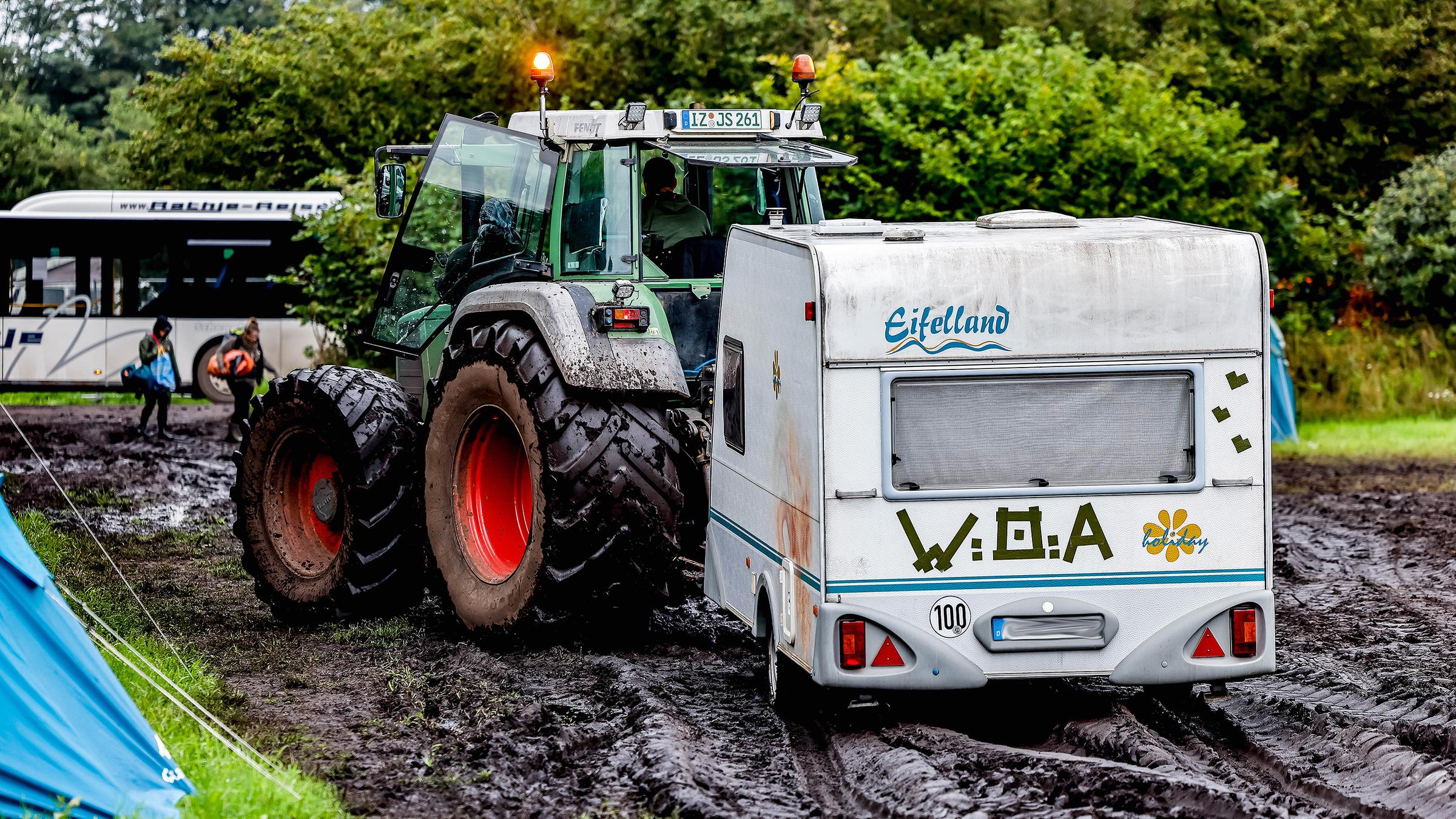 Traktor zieht einen Wohnwagen vom verschlammten Campinggelände des Wacken Open Air