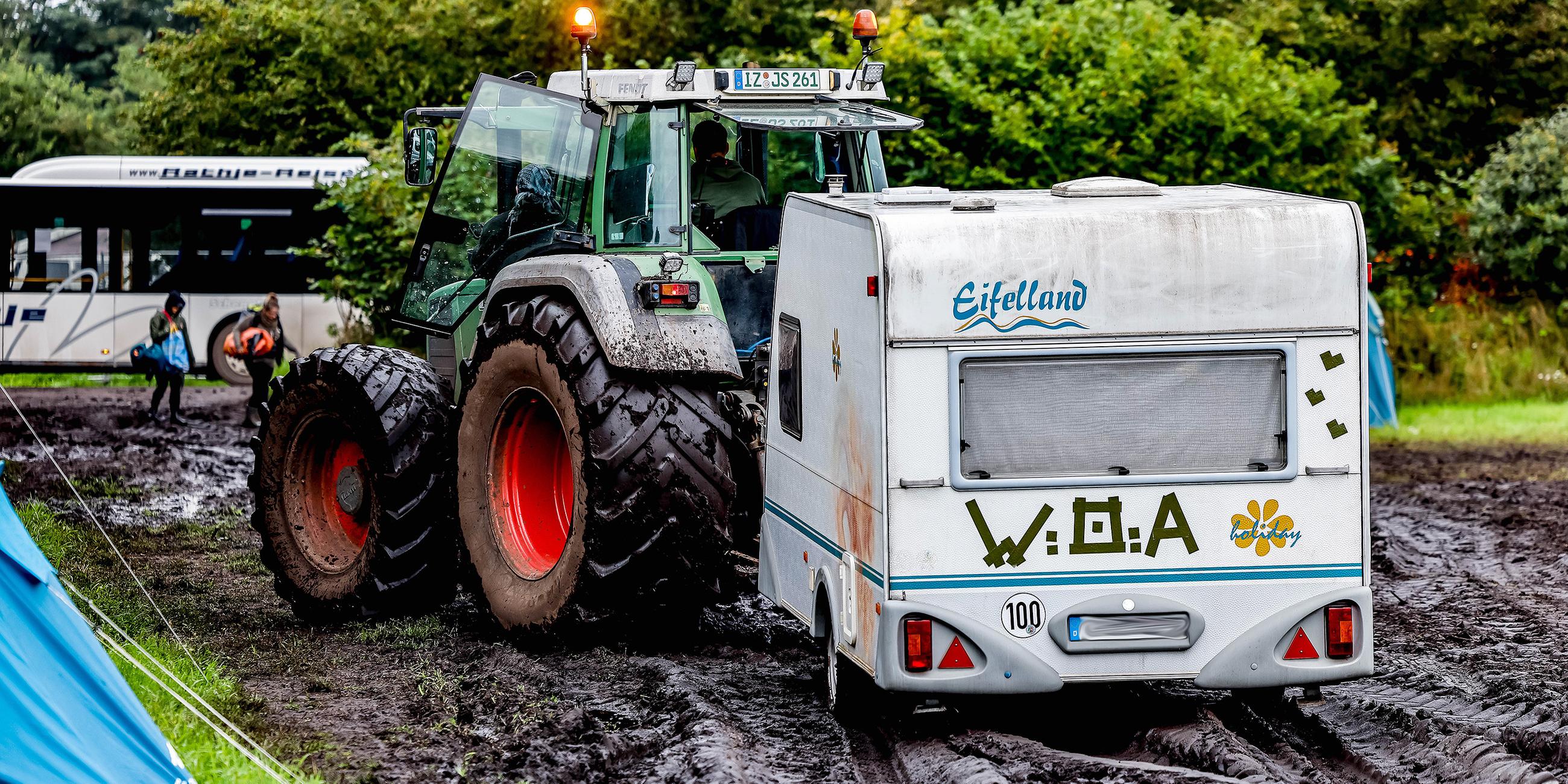 Traktor zieht einen Wohnwagen vom verschlammten Campinggelände des Wacken Open Air