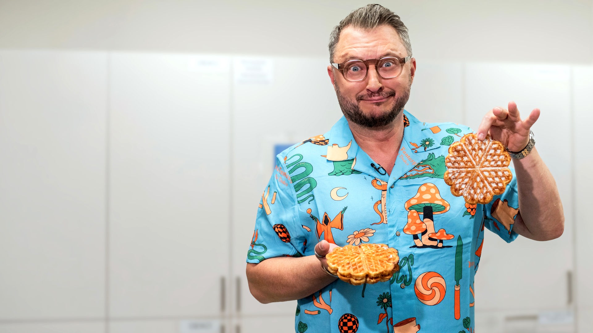 "besseresser Kids": Sebastian Lege steht in einer Küche, vor weißen Schränken und hält industriell gefertigte Waffeln in die Kamera.