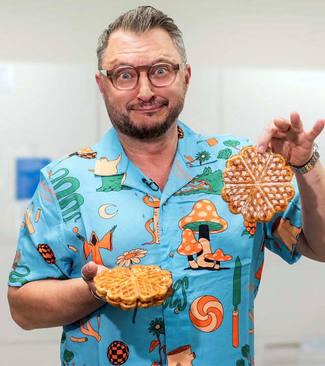 "besseresser Kids": Sebastian Lege steht in einer Küche, vor weißen Schränken und hält industriell gefertigte Waffeln in die Kamera.