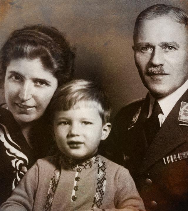 Ein Familienfoto aus den 1930er Jahren. Ein strahlender, gut frisierter kleiner Junge zwischen der herausgeputzten Mutter und dem Vater mit Schnurrbart und in Uniform.