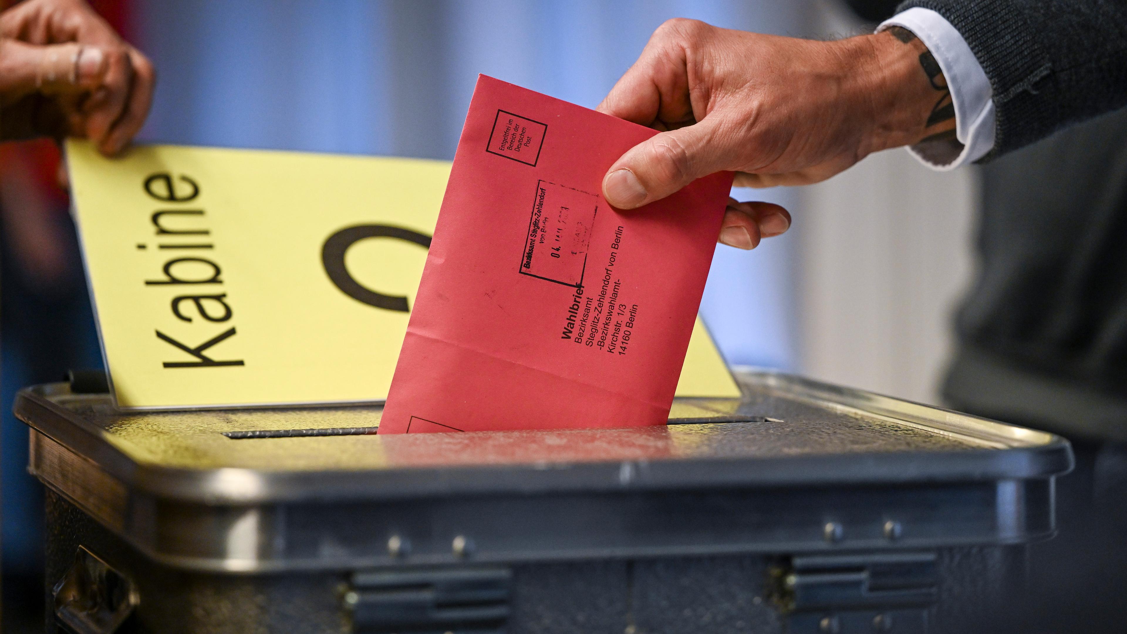 Zum Beginn der Briefwahl für die Wiederholungswahlen am 12. Februar wählt ein Mann im Rathaus Zehlendorf und steckt seine Stimmzettel in einem Briefumschlag für die Briefwahl in die Wahlurne