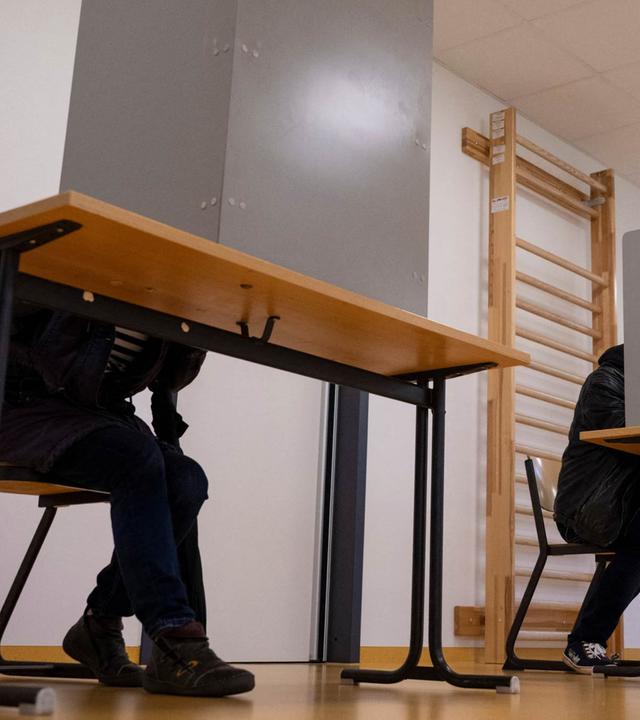 Drei Wahlkabinen mit zwei Menschen in Kabinen