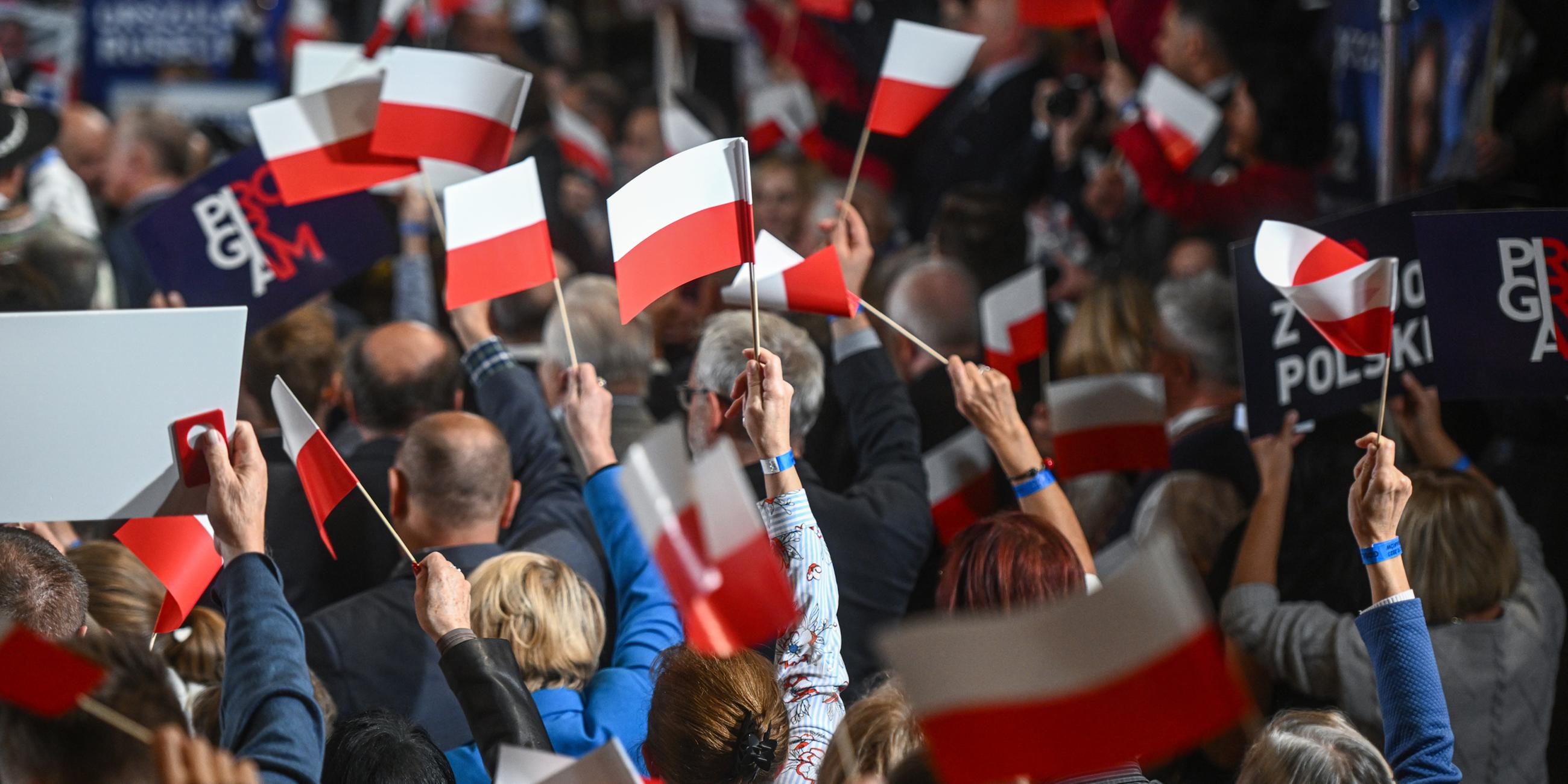  Anhänger und Abgeordnete der Partei Recht und Gerechtigkeit halten während einer Wahlkampfveranstaltung in Krakau am 11.10.2023 Transparente.
