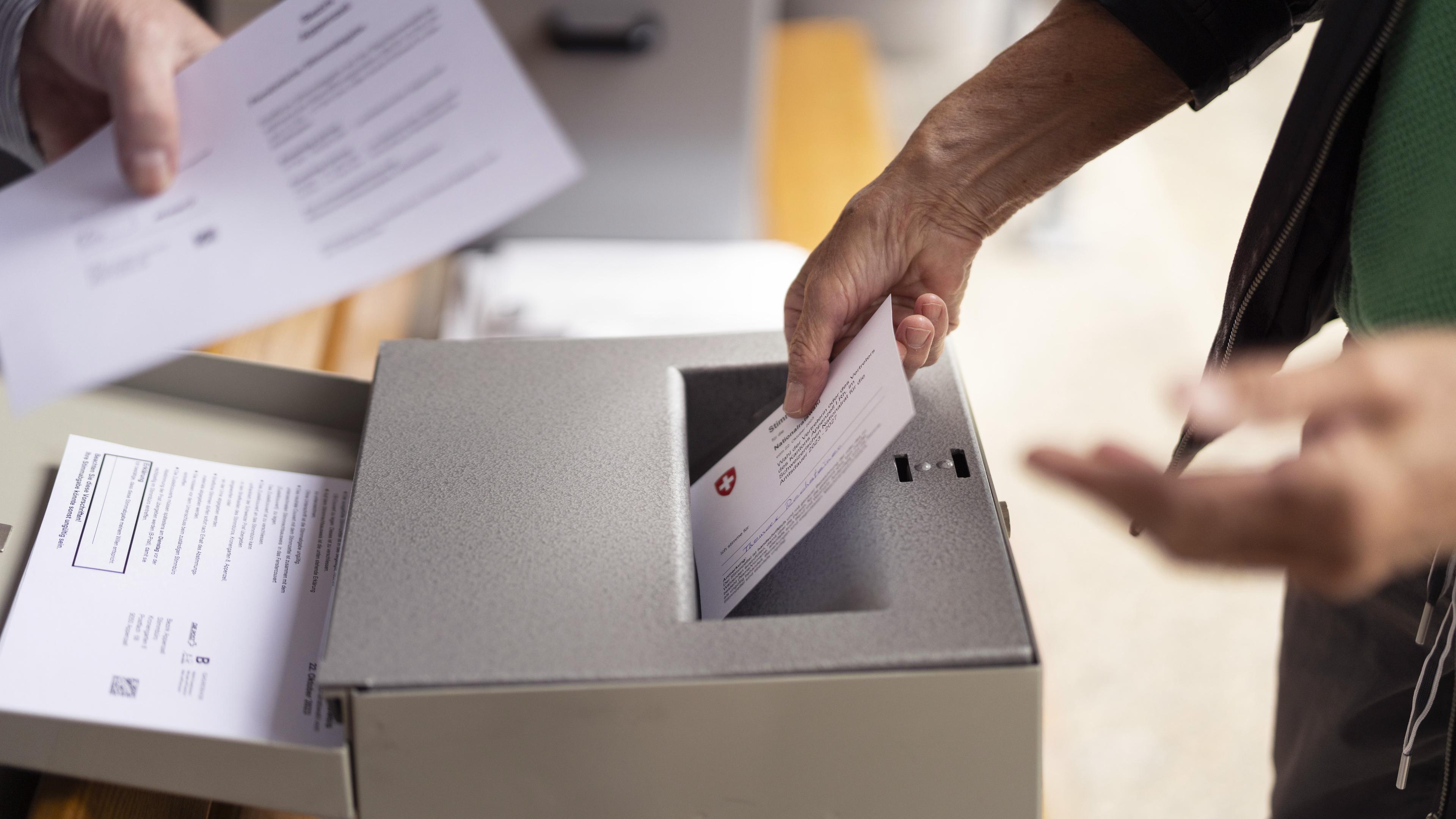 Personen werfen ihren Wahlzettel in die Wahlurne für die eidgenoessischen Wahlen in Appenzell. 