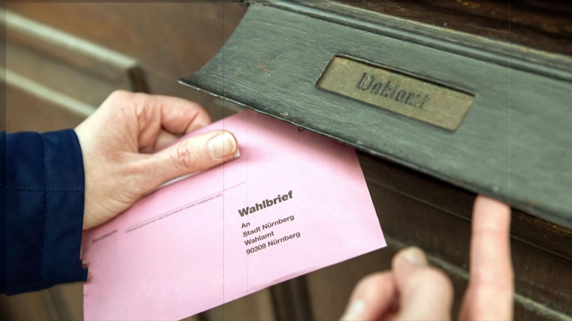 Person wirft einen Umschlag zur Briefwahl ein