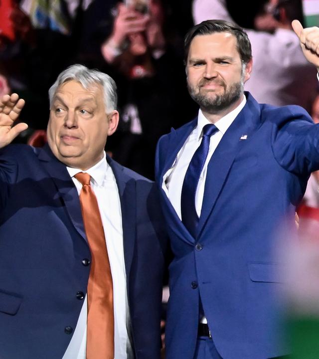 Links Viktor Orban und rechts J.D. Vance. Sie winken und stehen Arm um Arm