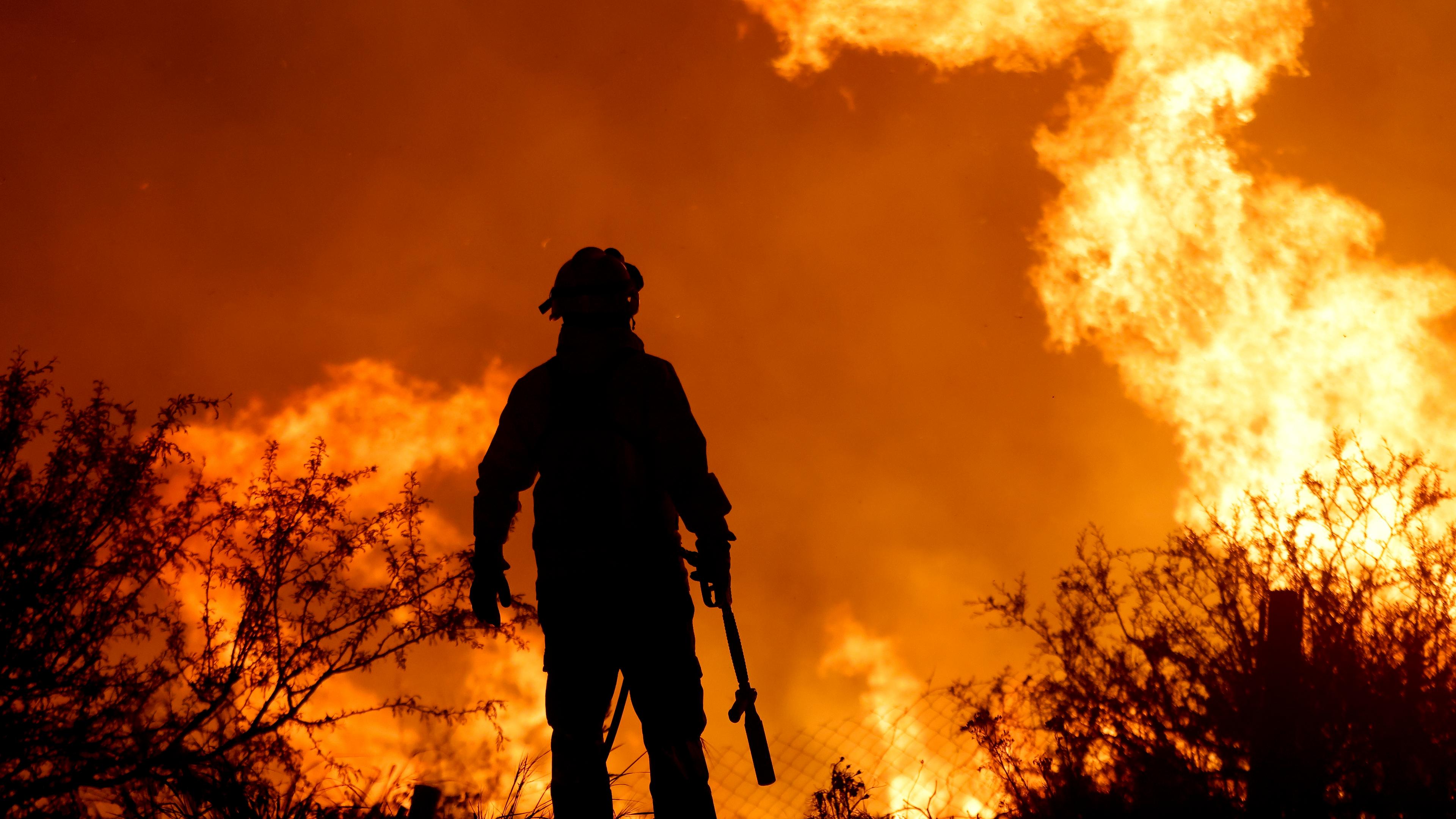  Ein Feuerwehrmann wird von den Flammen eines Waldbrandes am Stadtrand von Villa Carlos Paz umrahmt.