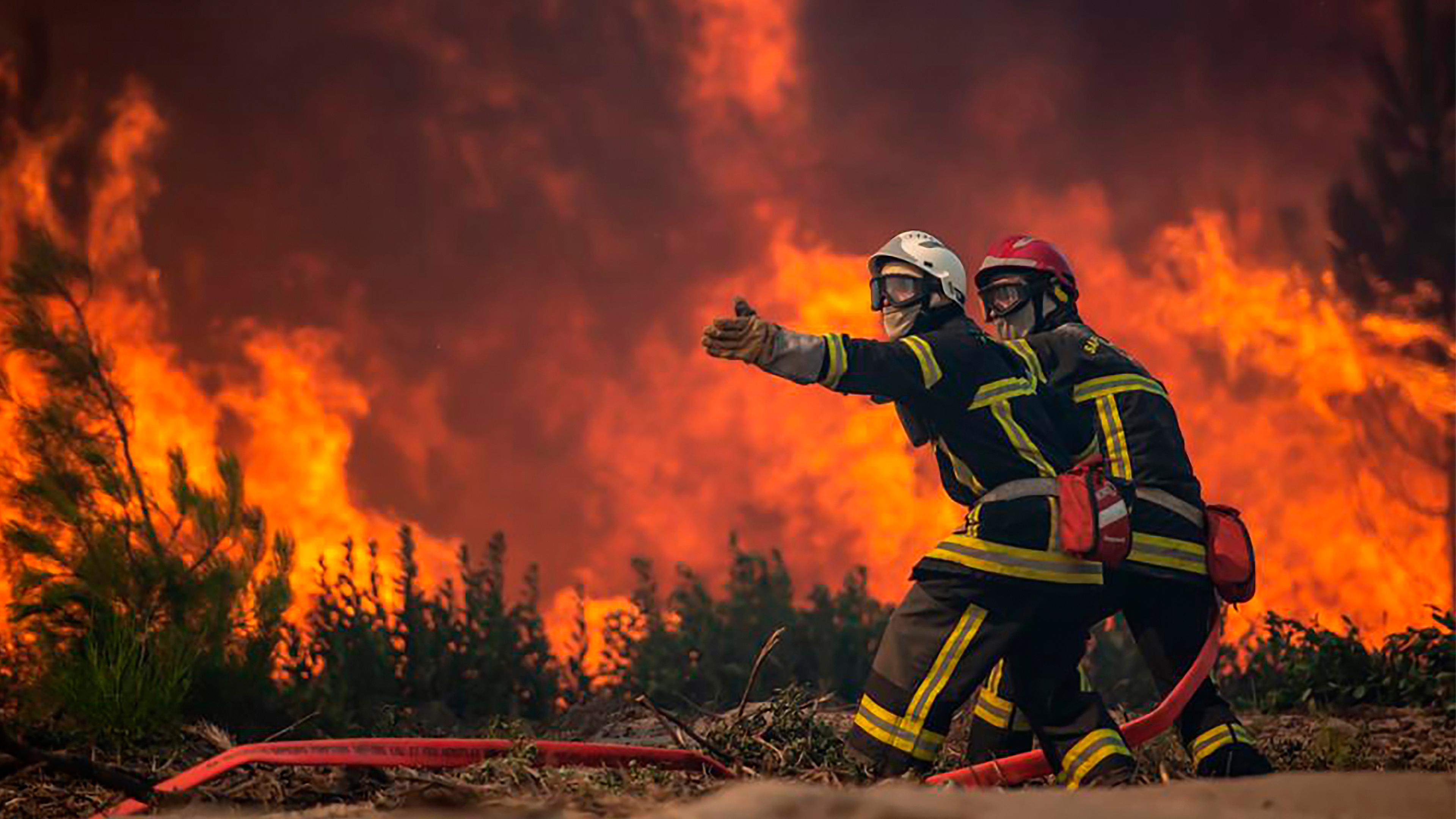Feuerwehrleute, die bei einem Waldbrand in La Test-de-Buch in Südfrankreich den Löschschlauch ausrollen, aufgenommen am 19.07.2022