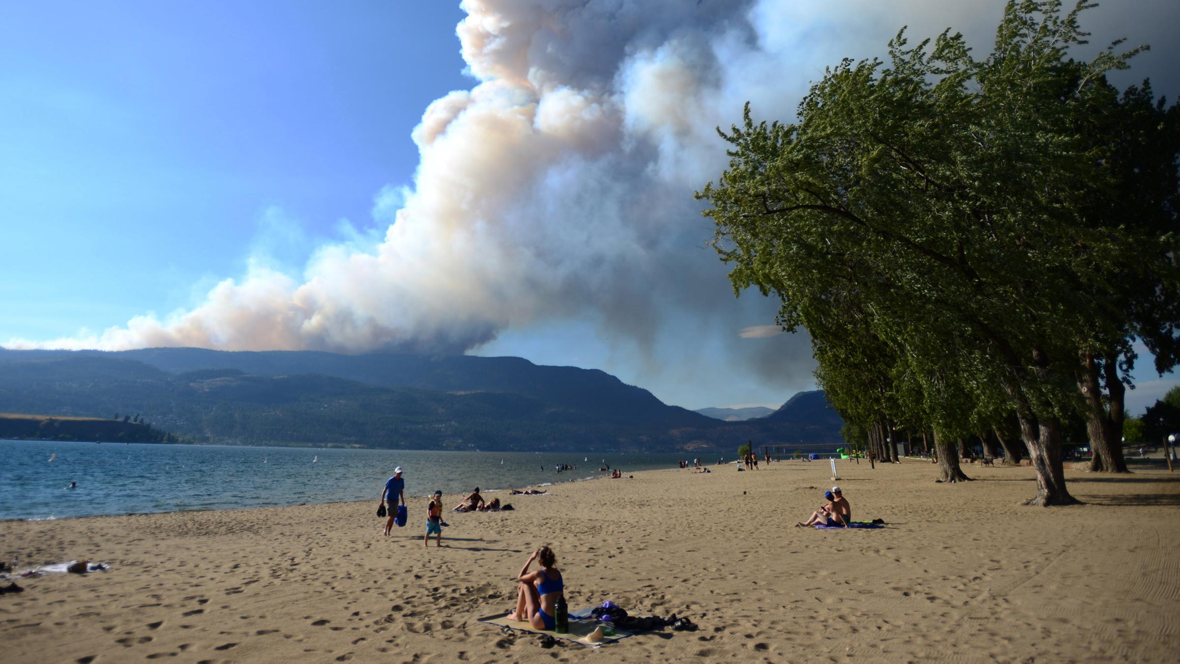 Strandbesucher beobachten, wie der Rauch des Feuers am McDougall Creek über den Okanagan Lakes aufsteigt. (17.08.2023)