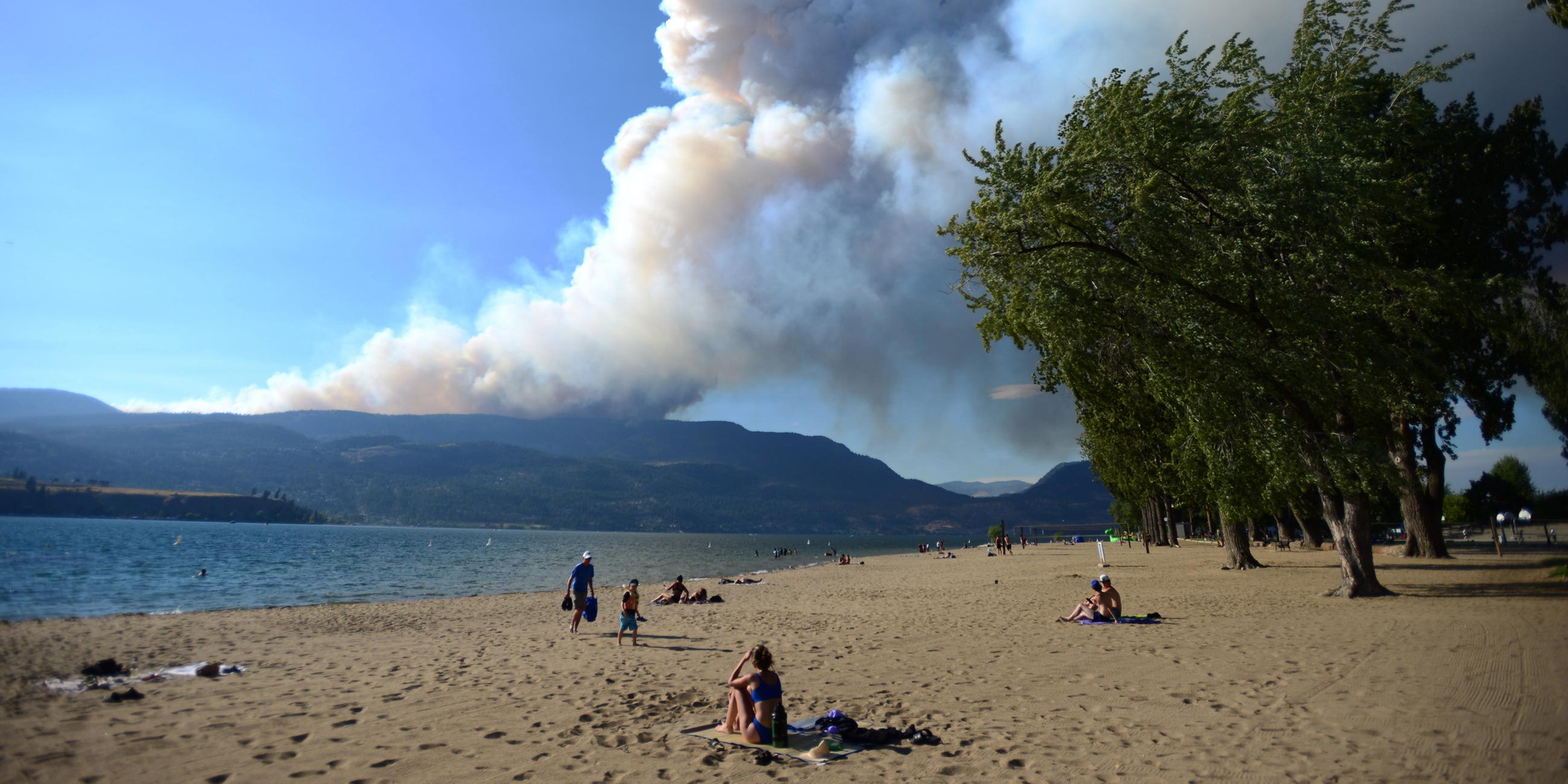 Strandbesucher beobachten, wie der Rauch des Feuers am McDougall Creek über den Okanagan Lakes aufsteigt. (17.08.2023)