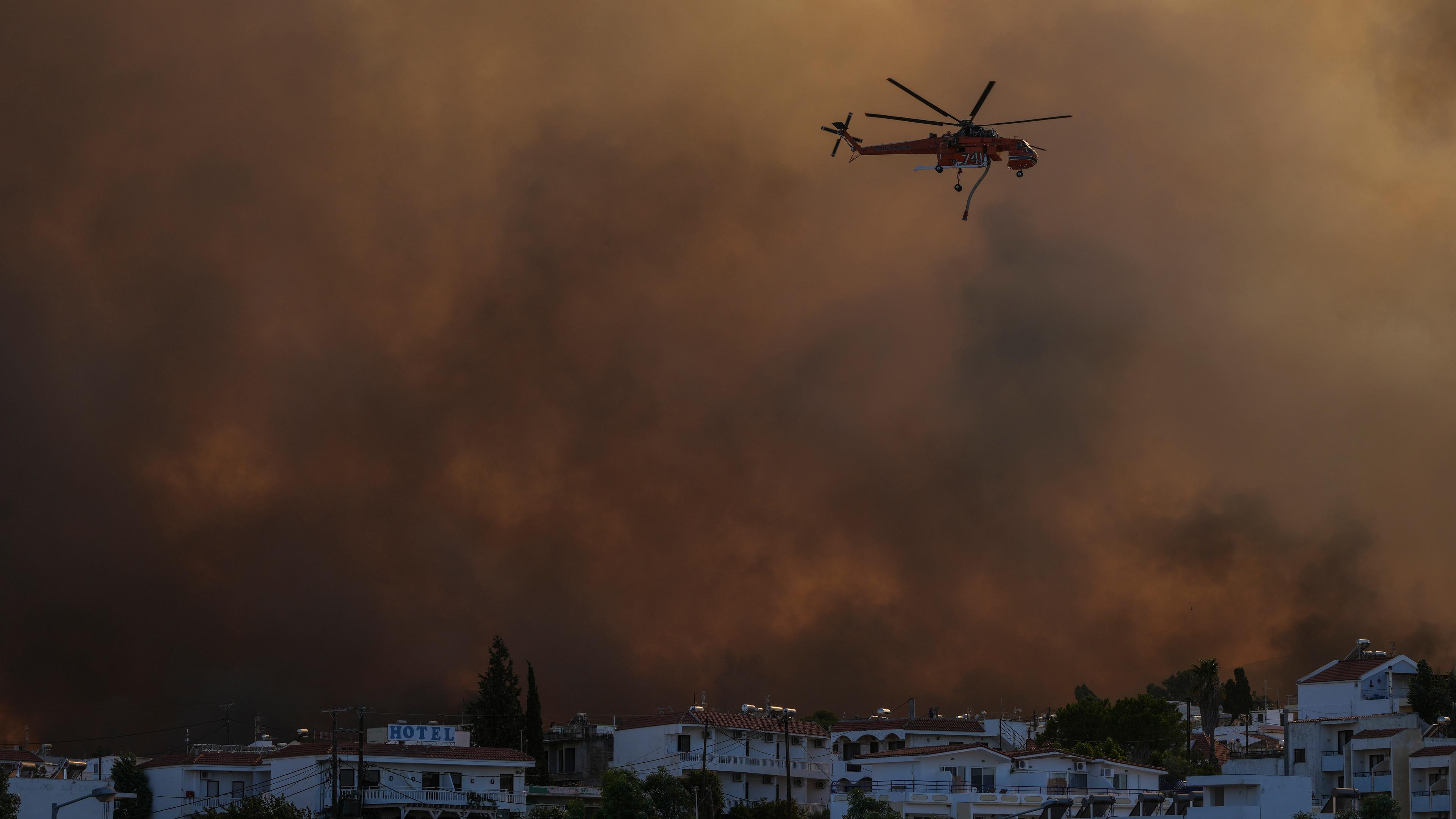 Ein Hubschrauber fliegt über einem Waldbrand im Dorf Gennadi.