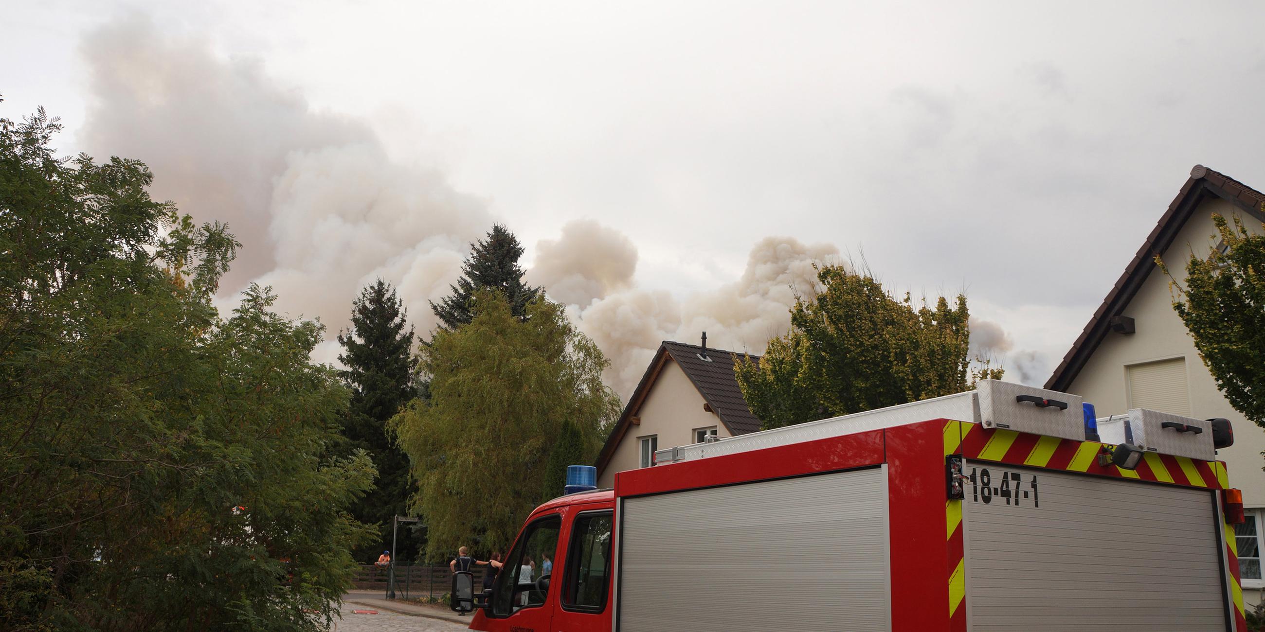 Das Feuer hat sich bis Frohnsdorf ausgebreitet. Rauch steigt neben einem Haus am Ortsrand auf.