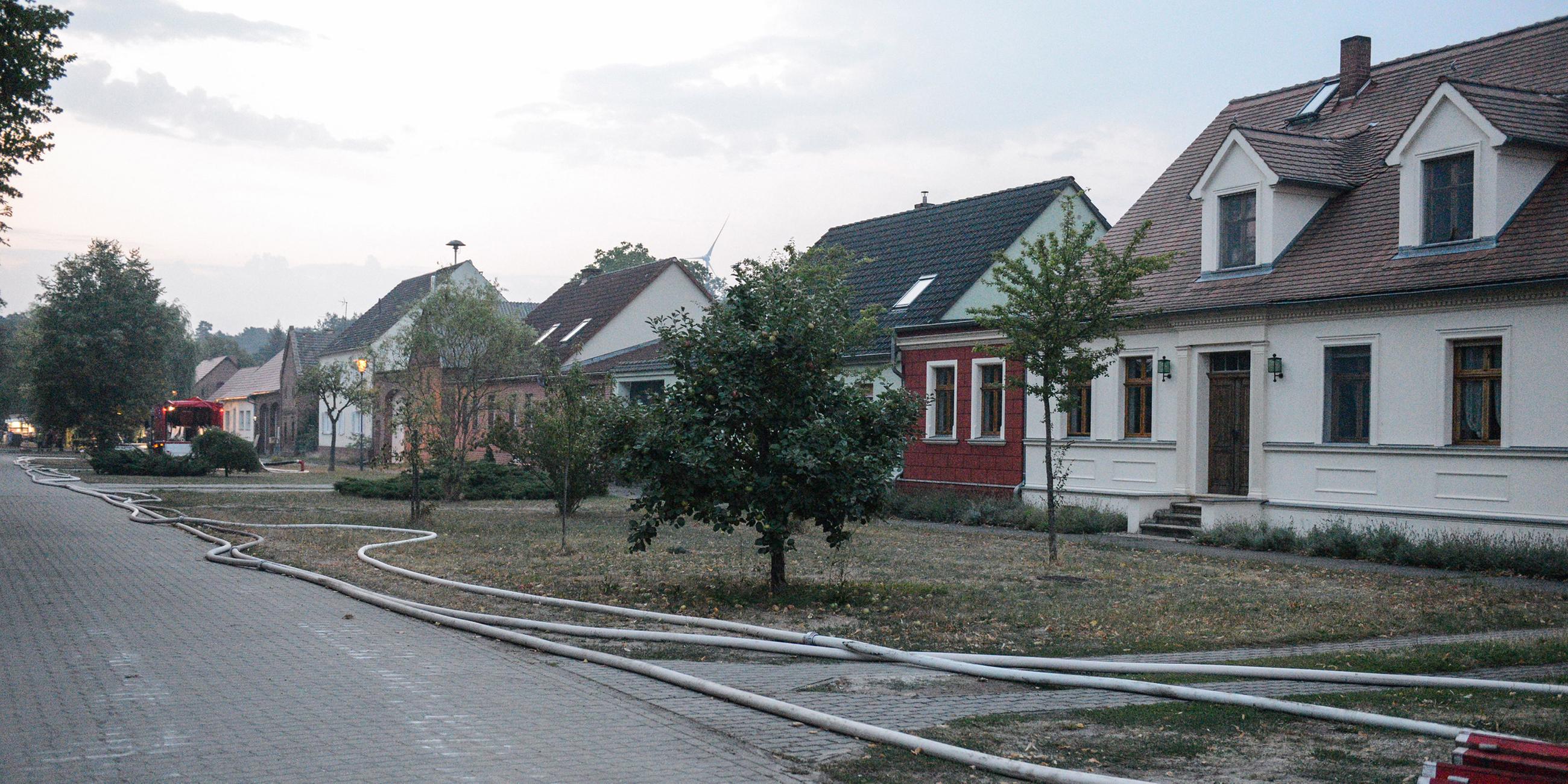 Nach der Evakuierung von Klausdorf liegen Löschschläuche an einer Straße.