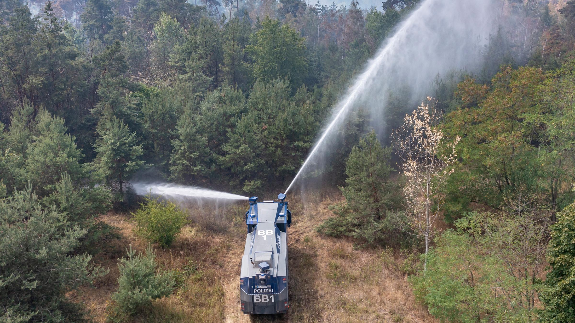 Ein Wasserwerfer der Brandenburger Polizei löscht einen Waldbrand am 27.07.2022 in Falkenberg, Brandenburg