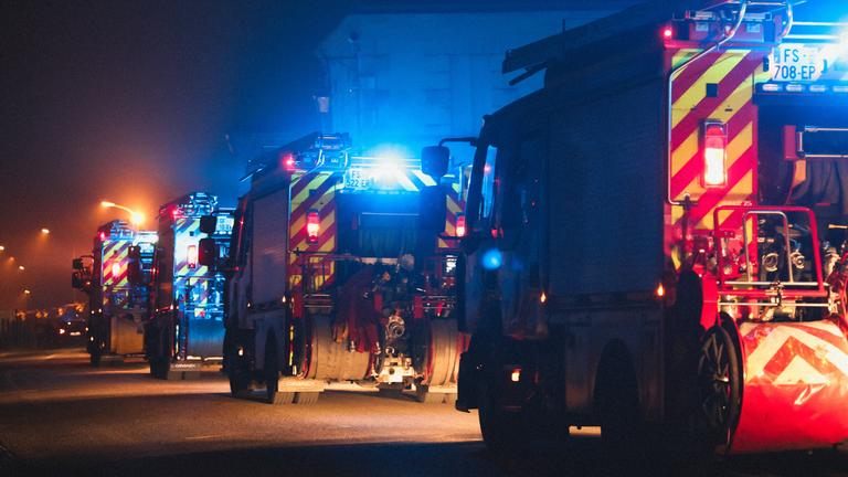 Eine Kolonne aus Feuerwehr-Wägen fährt hintereinander eine Straße entlang.