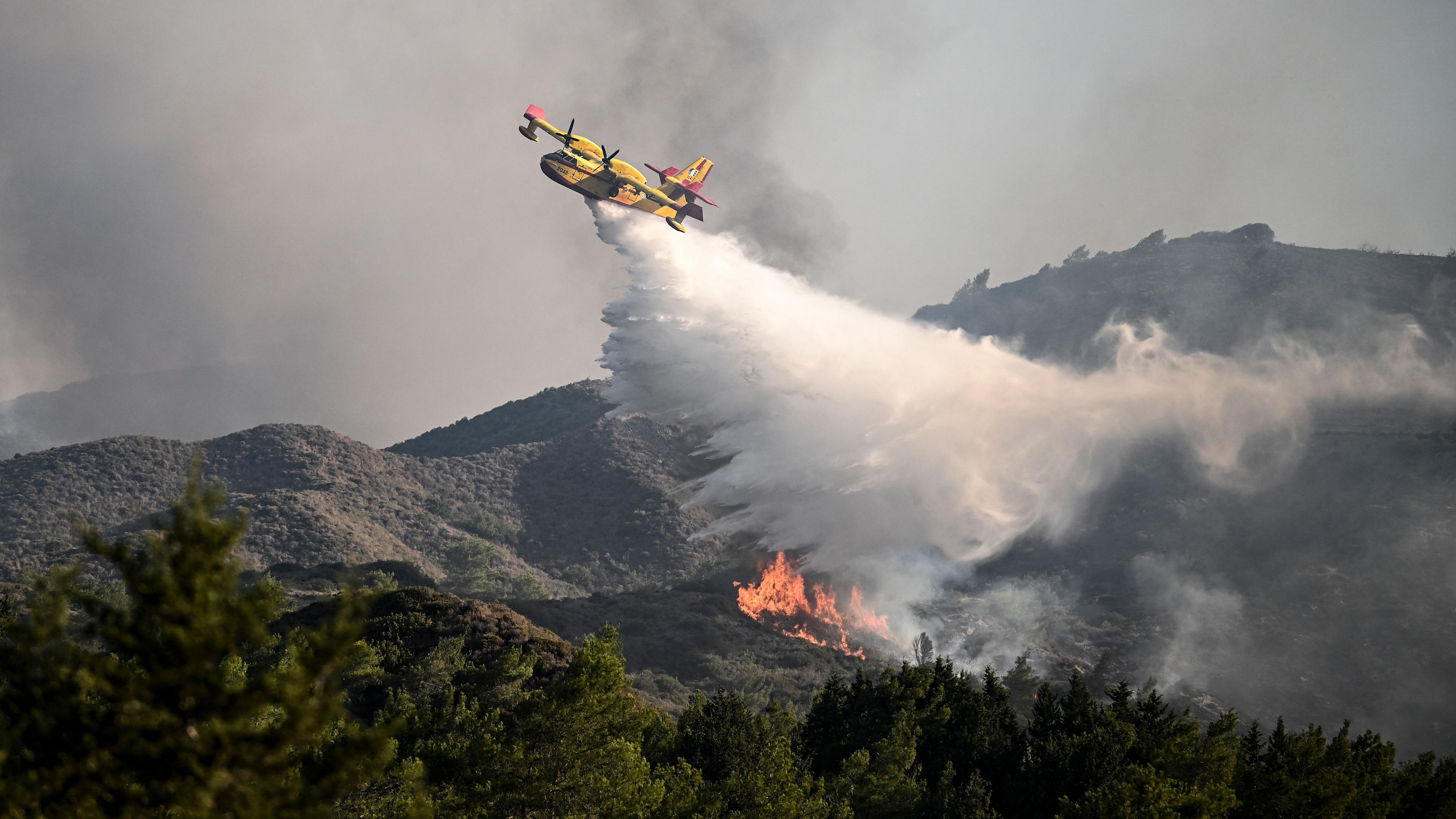 Ein Löschflugzeug wirft am 25. Juli 2023 Wasser über einem Waldbrand in der Nähe des Dorfes Vati im Süden der griechischen Insel Rhodos, aufgenommen am 24.07.2023