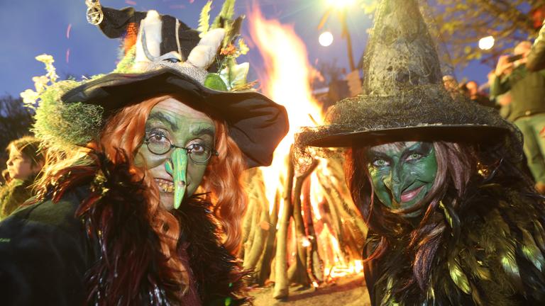 Zwei als Hexe kostümierte Frauen stehen am Walpurgisfeuer auf dem Hexentanzplatz. 