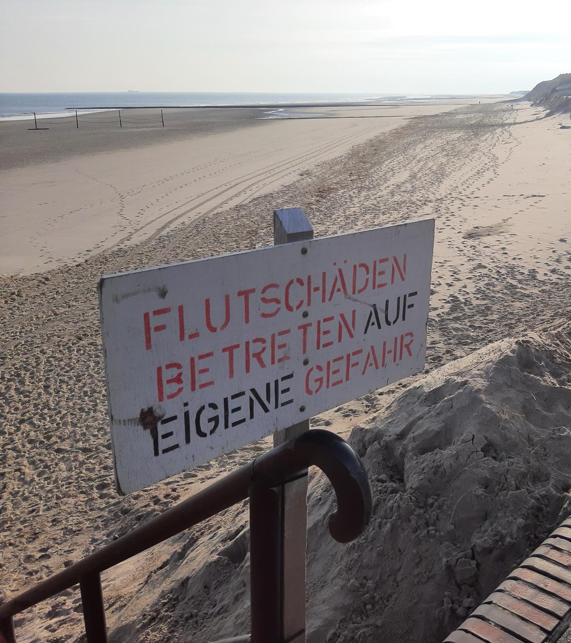 Ein Schild mit der Aufschrift "Flutschäden Betreten auf eigene Gefahr" weist am Strand der Insel Wangerooge auf fehlenden Sand am Strand hin.