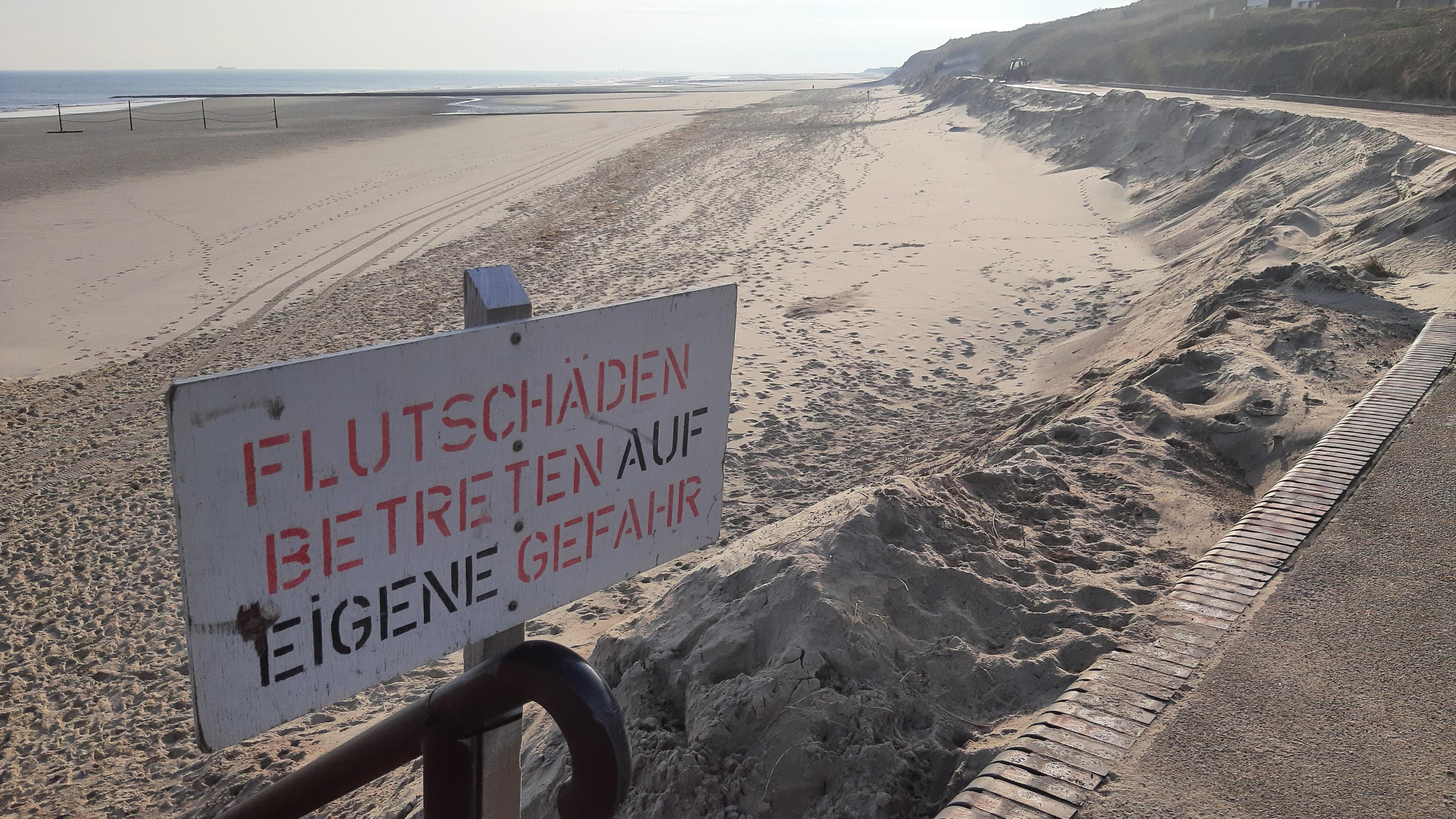 Ein Schild mit der Aufschrift "Flutschäden Betreten auf eigene Gefahr" weist am Strand der Insel Wangerooge auf fehlenden Sand am Strand hin.