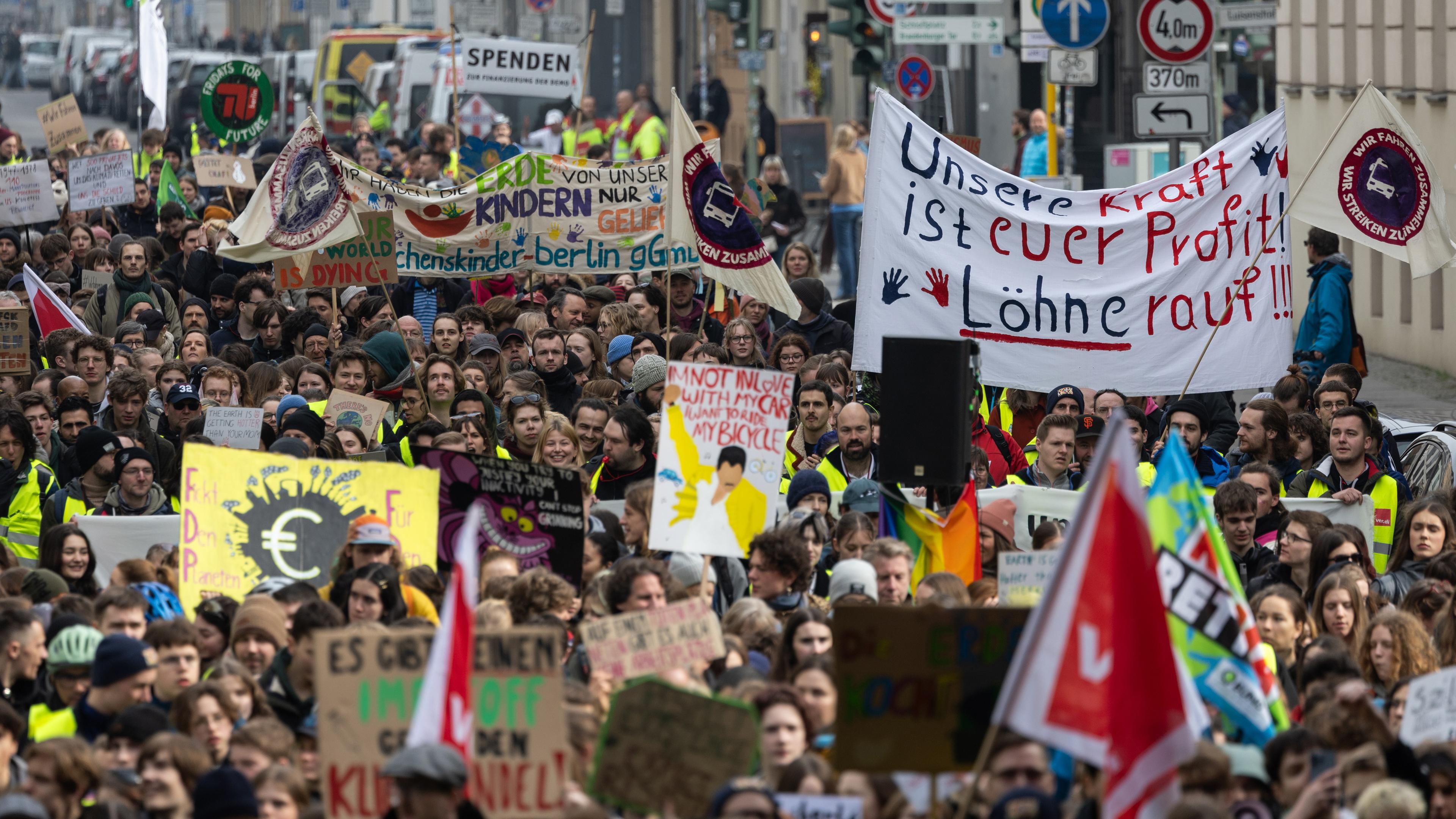Berlin: Demonstrierende halten Banner, Flaggen und Schilder hoch während der Demonstration.