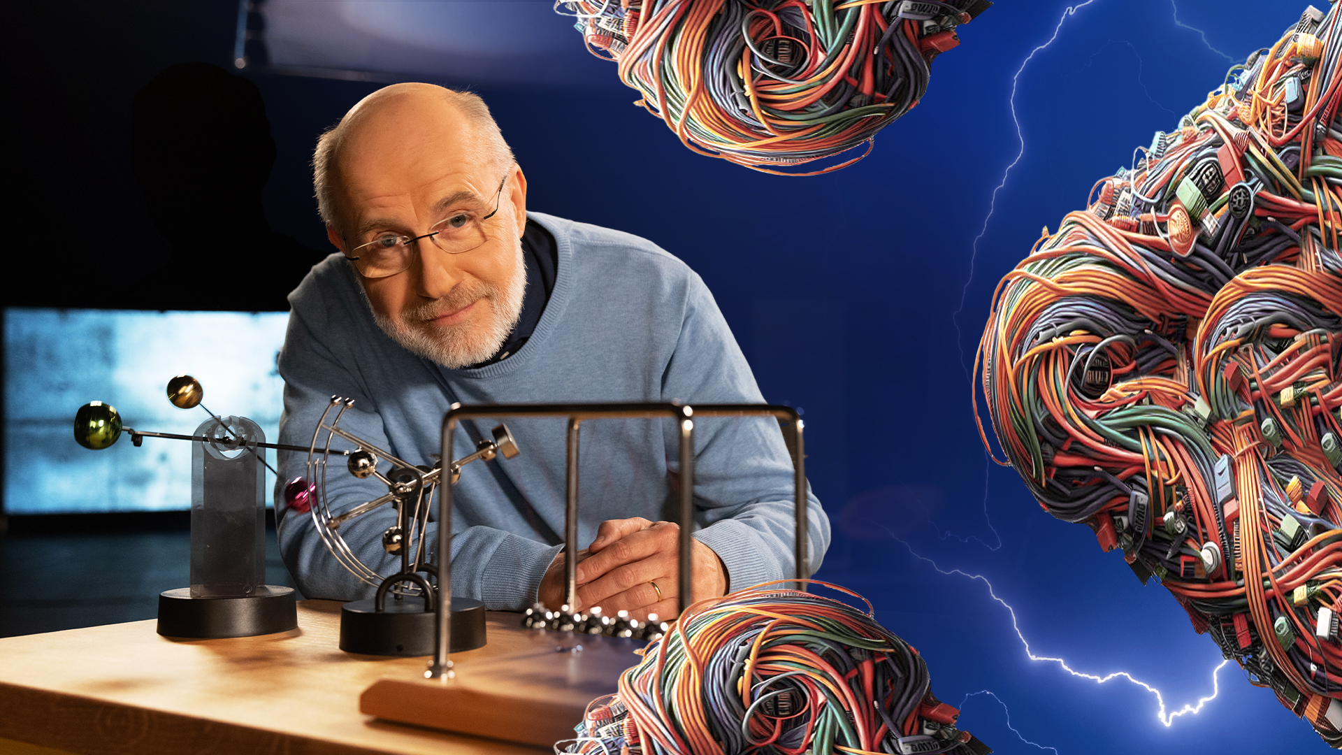 Harald Lesch steht neben einem Perpetuum-Mobile. Rechts im Bild deuten bunte Kabel ein X an und Biltze im Hinterrgund symbolisieren das Thema Energie