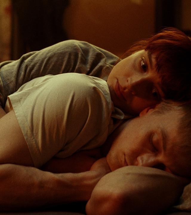 "Was du von mir sehen kannst": Adam (Julius Nitschkoff) liegt auf der Seite im Bett und schläft, während sich Gwen (Sina Genschl) an ihn kuschelt und die Augen offen hat.