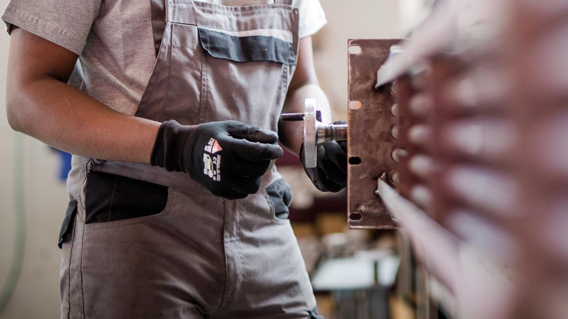 Ein Geflüchteter arbeitet an einer Maschine.