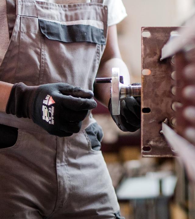 Ein Geflüchteter arbeitet an einer Maschine.