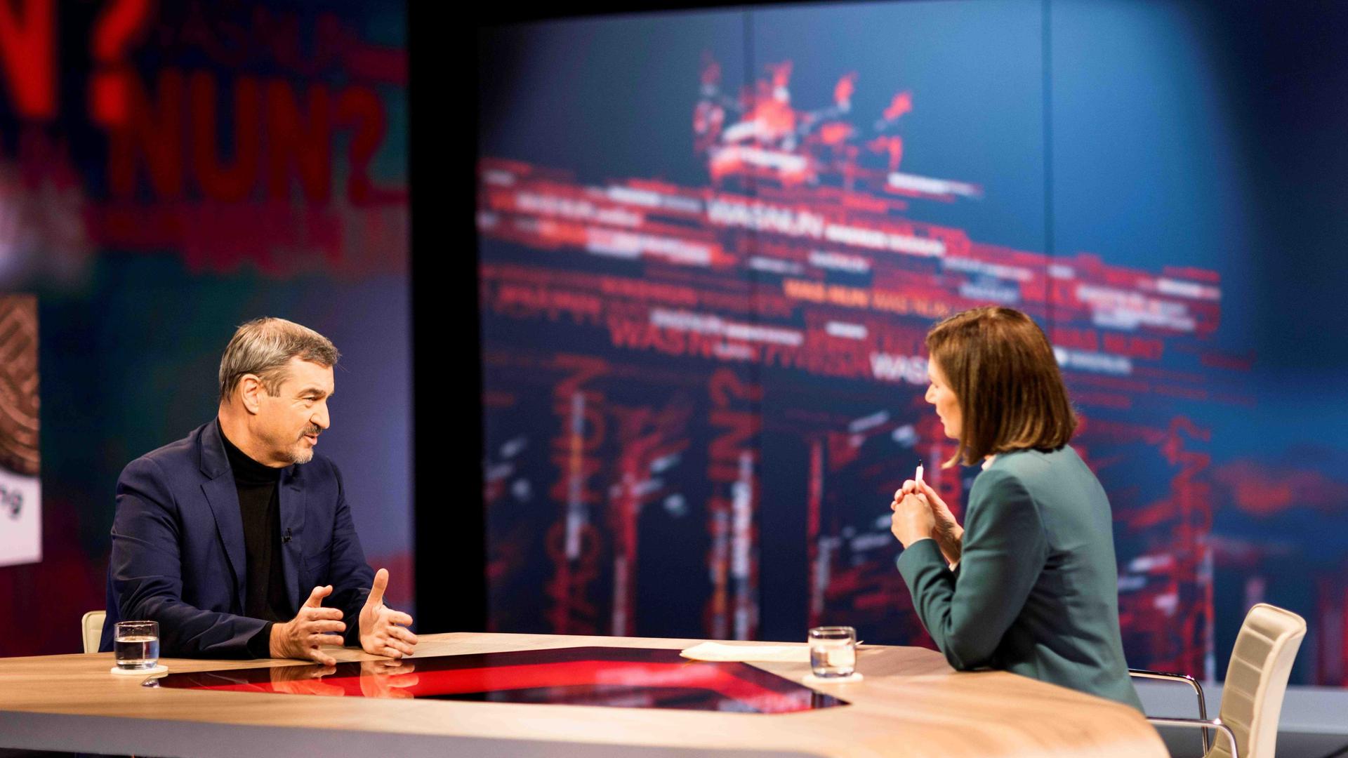 Markus Söder hinter einem Sprecherpult. Im Hintergrund eine blaue Leinwand. 