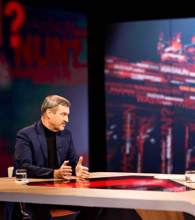 Markus Söder hinter einem Sprecherpult. Im Hintergrund eine blaue Leinwand. 