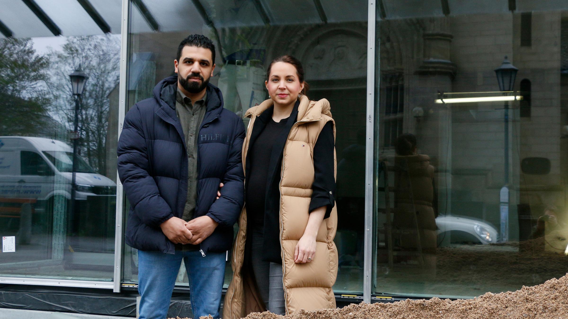 Nora und Soufyan Nechad stehen vor ihrem zukünftigen Optikergeschäft und schauen in die Kamera.