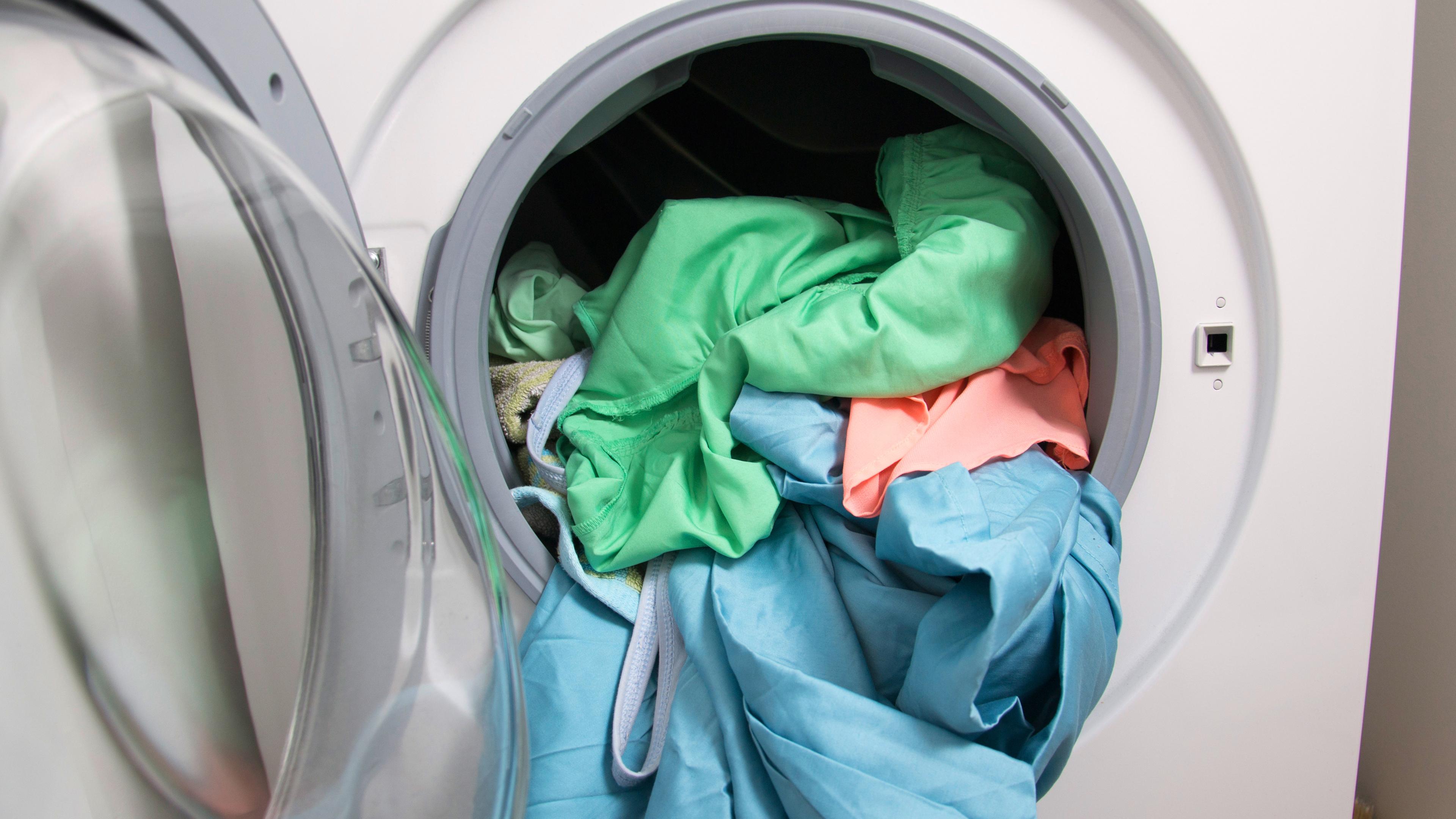 In einer geöffneten Waschmaschine befindet sich bunte Wäsche.