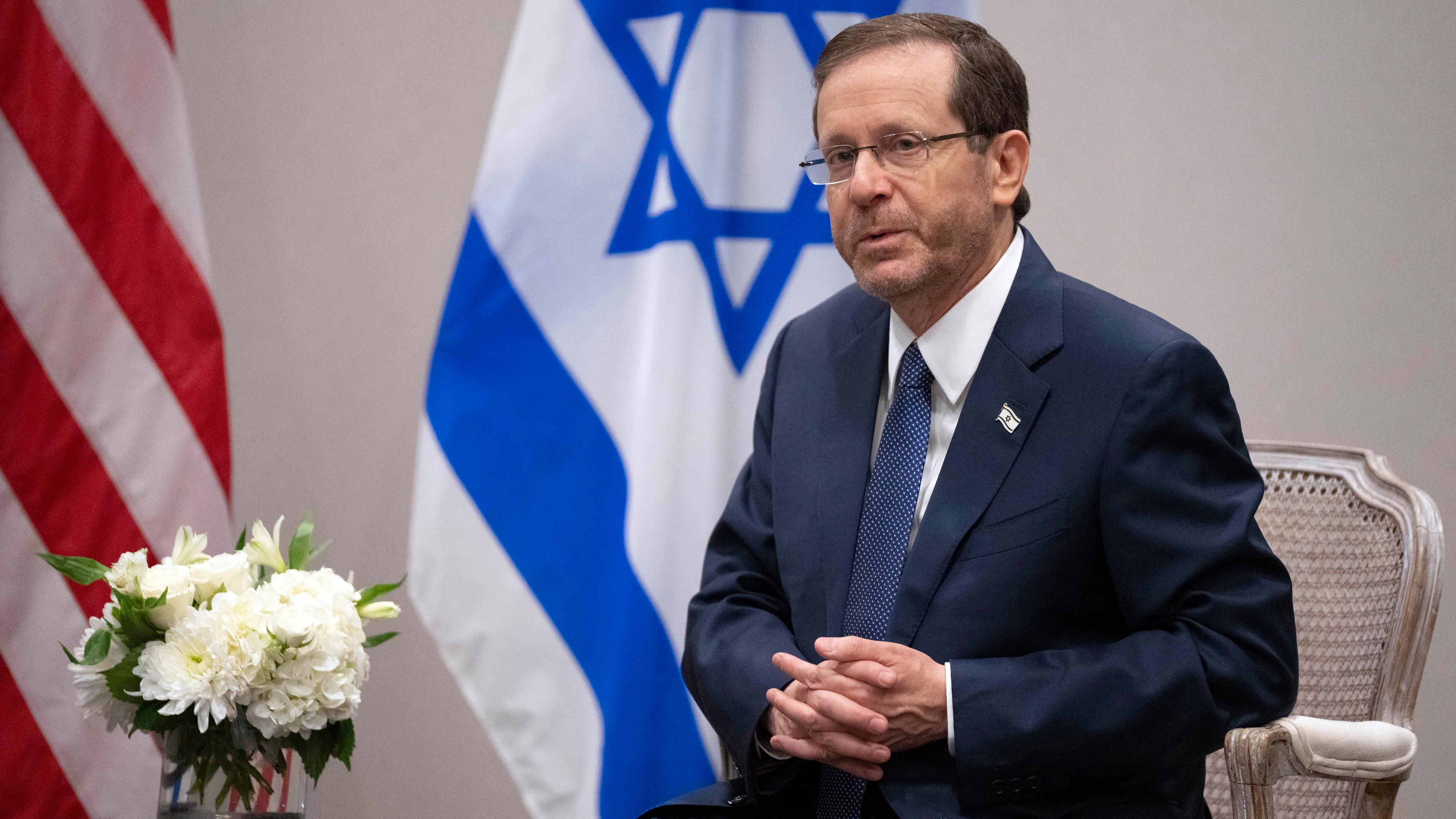 Israels Präsident Isaac Herzog vor einer israelischen und amerikanischen Flagge.