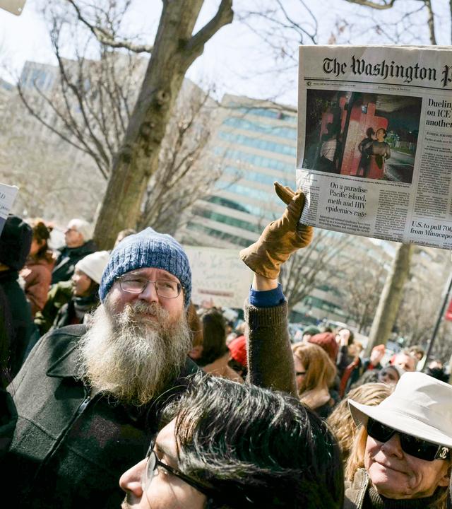 Demonstranten halten ein Exemplar der Zeitung Washington Post und Plakate hoch.