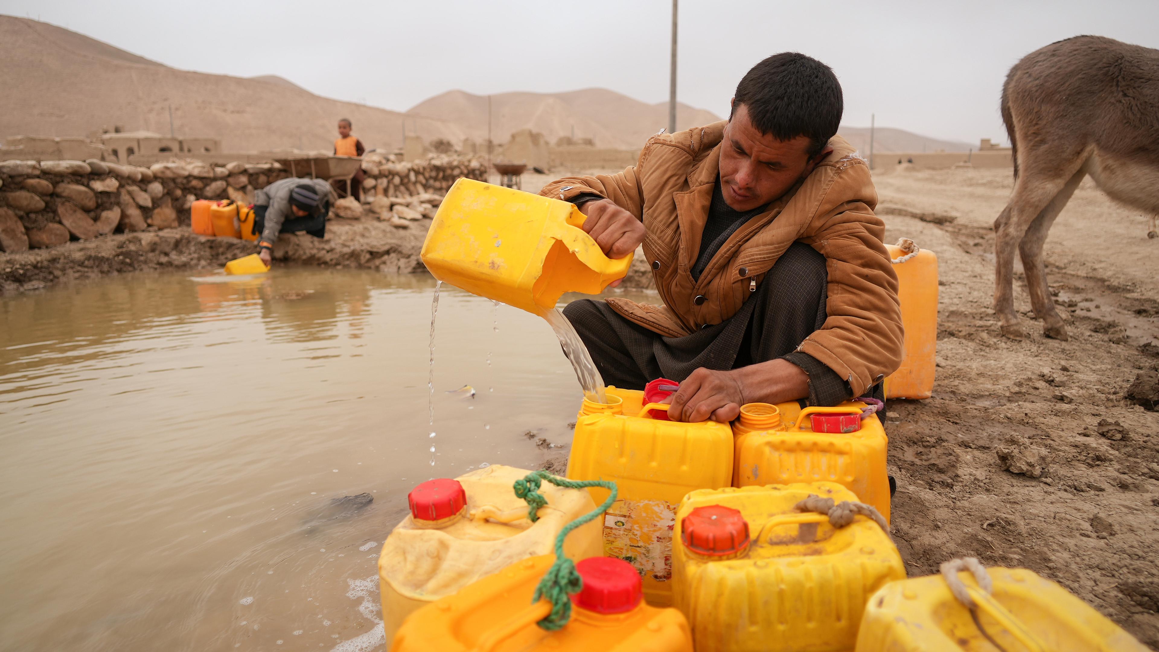 Afghanischer Mann füllt Ölkanister mit Wasser in der Nähe eines improvisierten Staudamm, aufgenommen am 13.12.2021