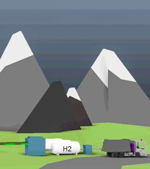 Es ist eine Landschaft mit Wiese und Bergen zu sehen. Rechts befinden sich Wasserstofftanks. Links sind Windräder.