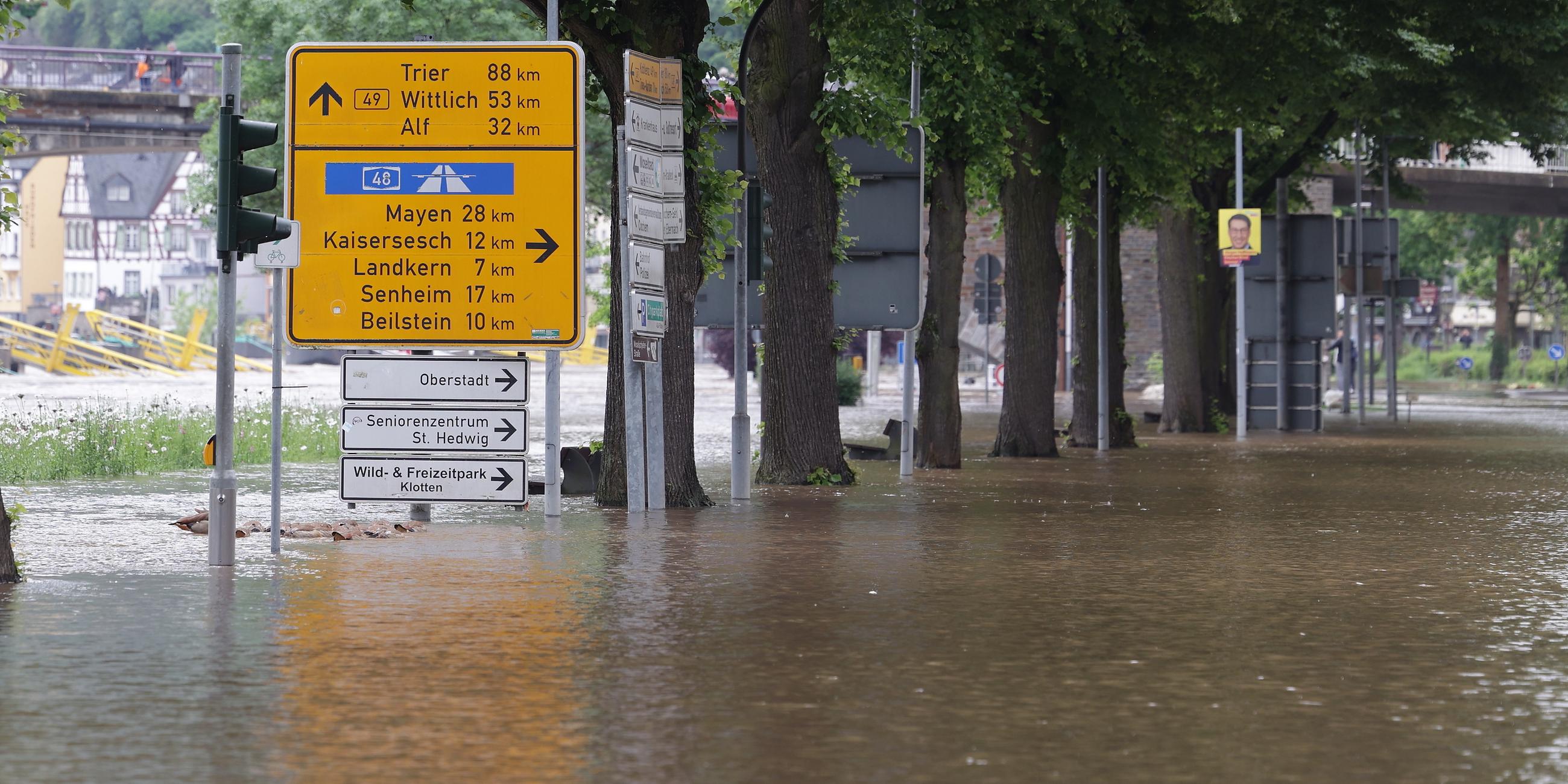 Ein Wegweiser steht zwischen zwei überfluteten Straßen