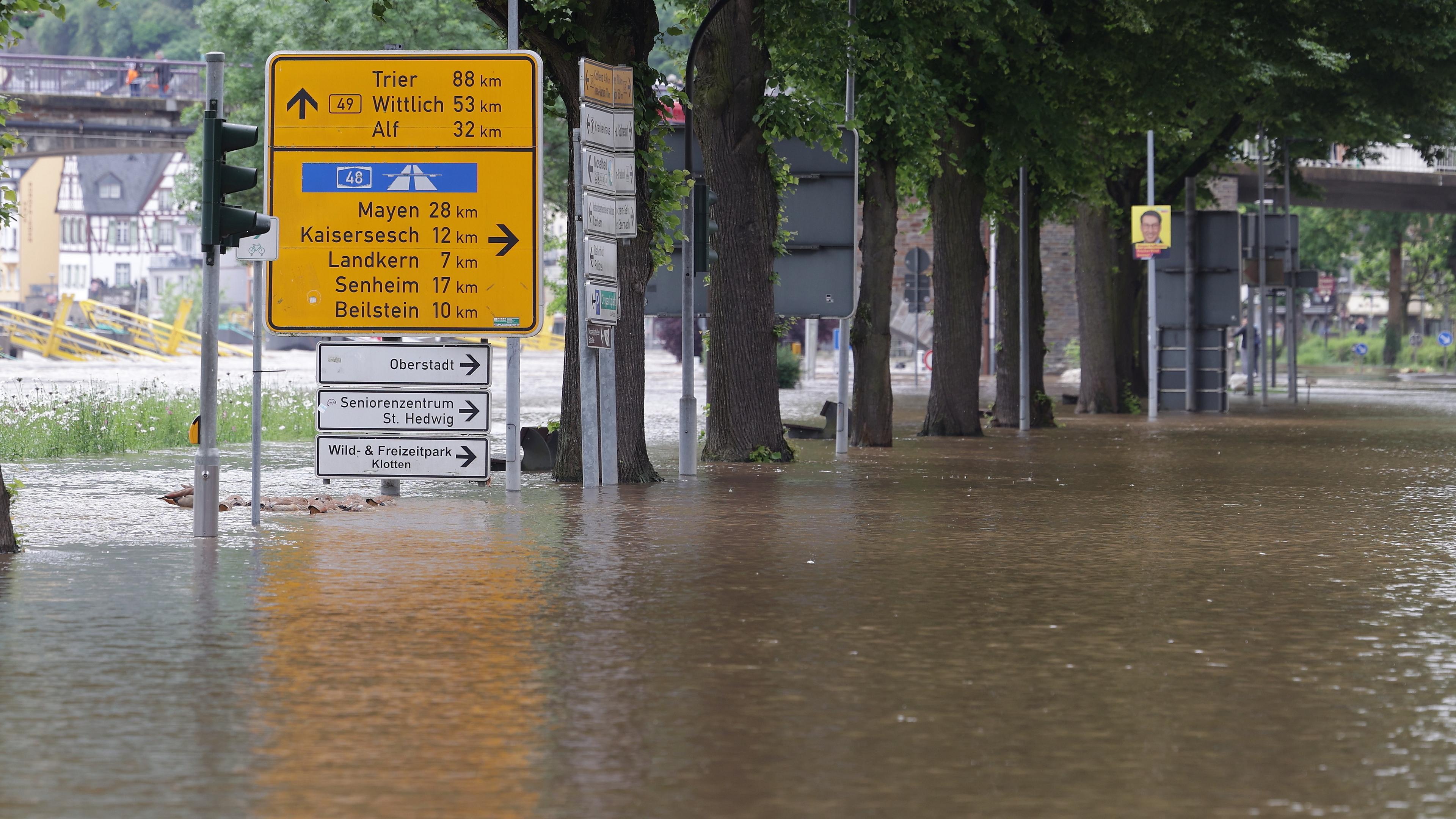 Ein Wegweiser steht zwischen zwei überfluteten Straßen