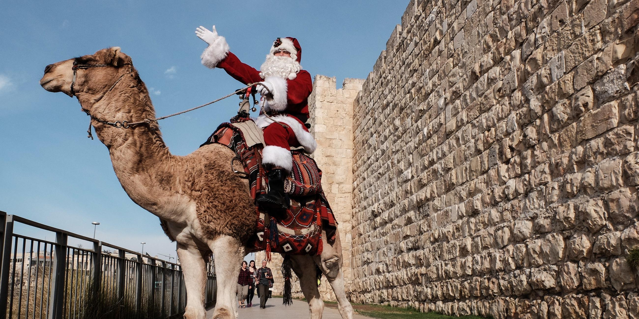 Ein als Weihnachtsmann verkleideter Mann reitet am 21.12.2017 in Jerusalem auf einem Kamel