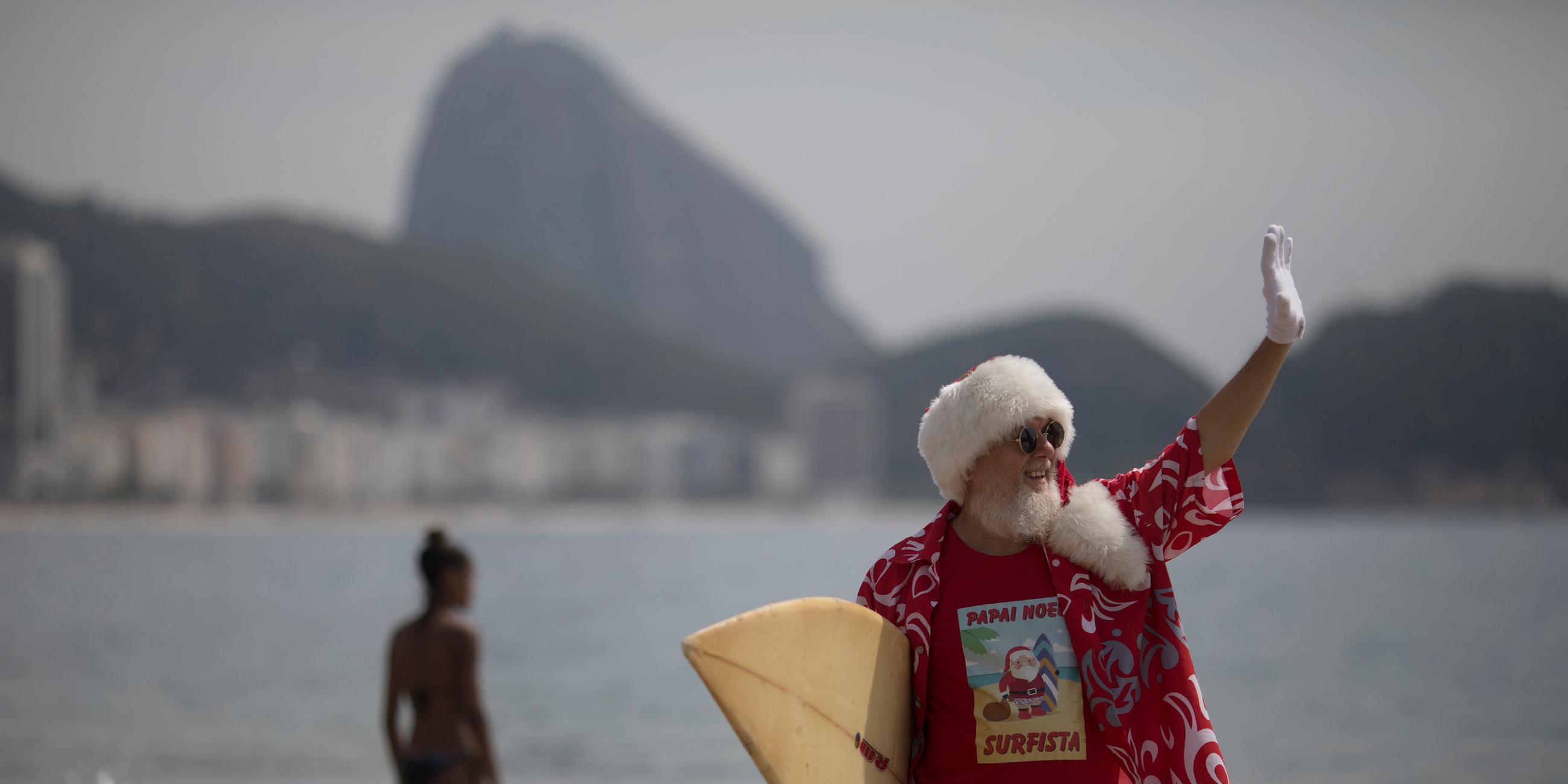 Ein Surfer im Weihnachtsmannverkleidung steht am 21.12.2017 am Strand von Rio de Janeiro (Brasilien)